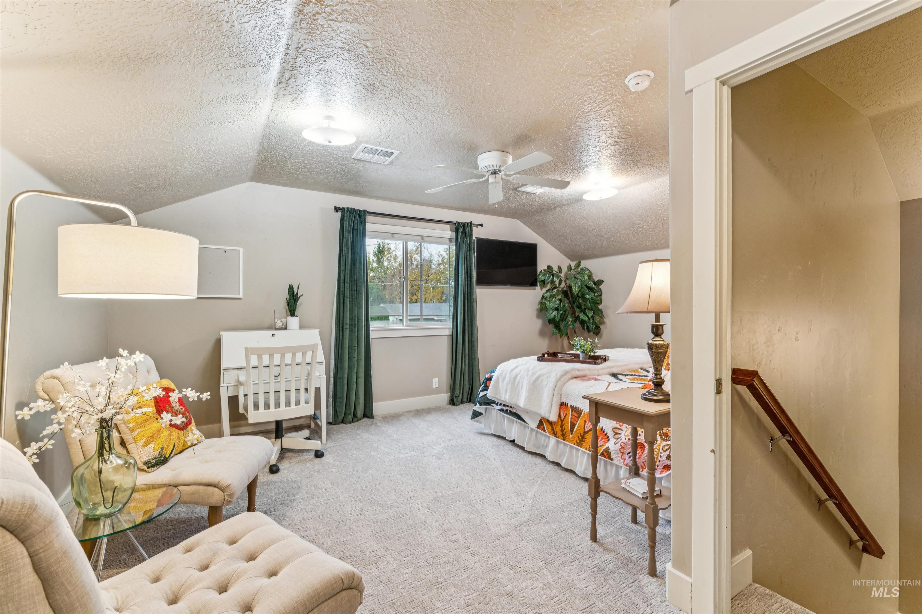 Bedroom featuring a textured ceiling, carpet floors, vaulted ceiling, and ceiling fan