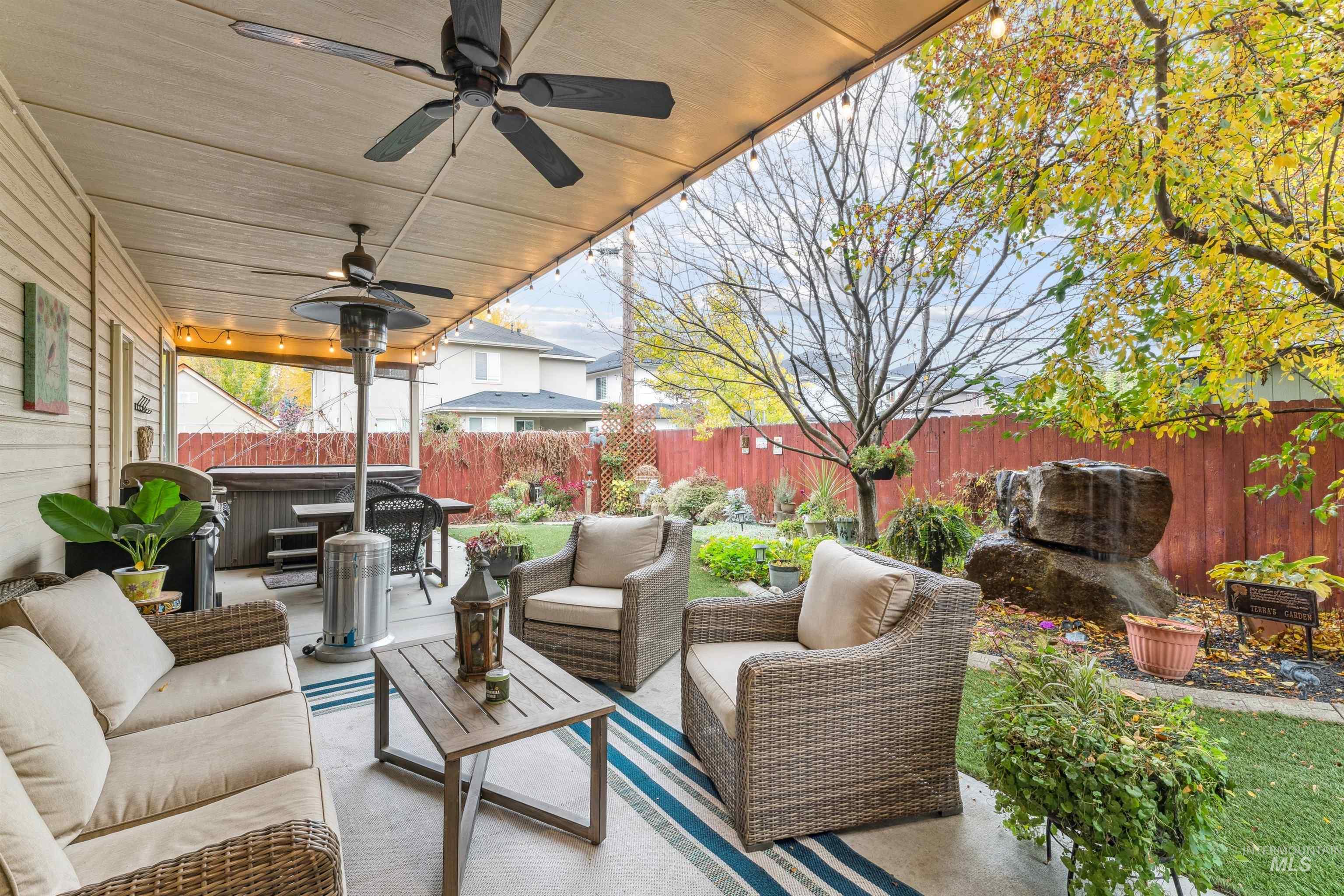 Fenced backyard with an outdoor hangout area, a ceiling fan, a patio area, and a hot tub