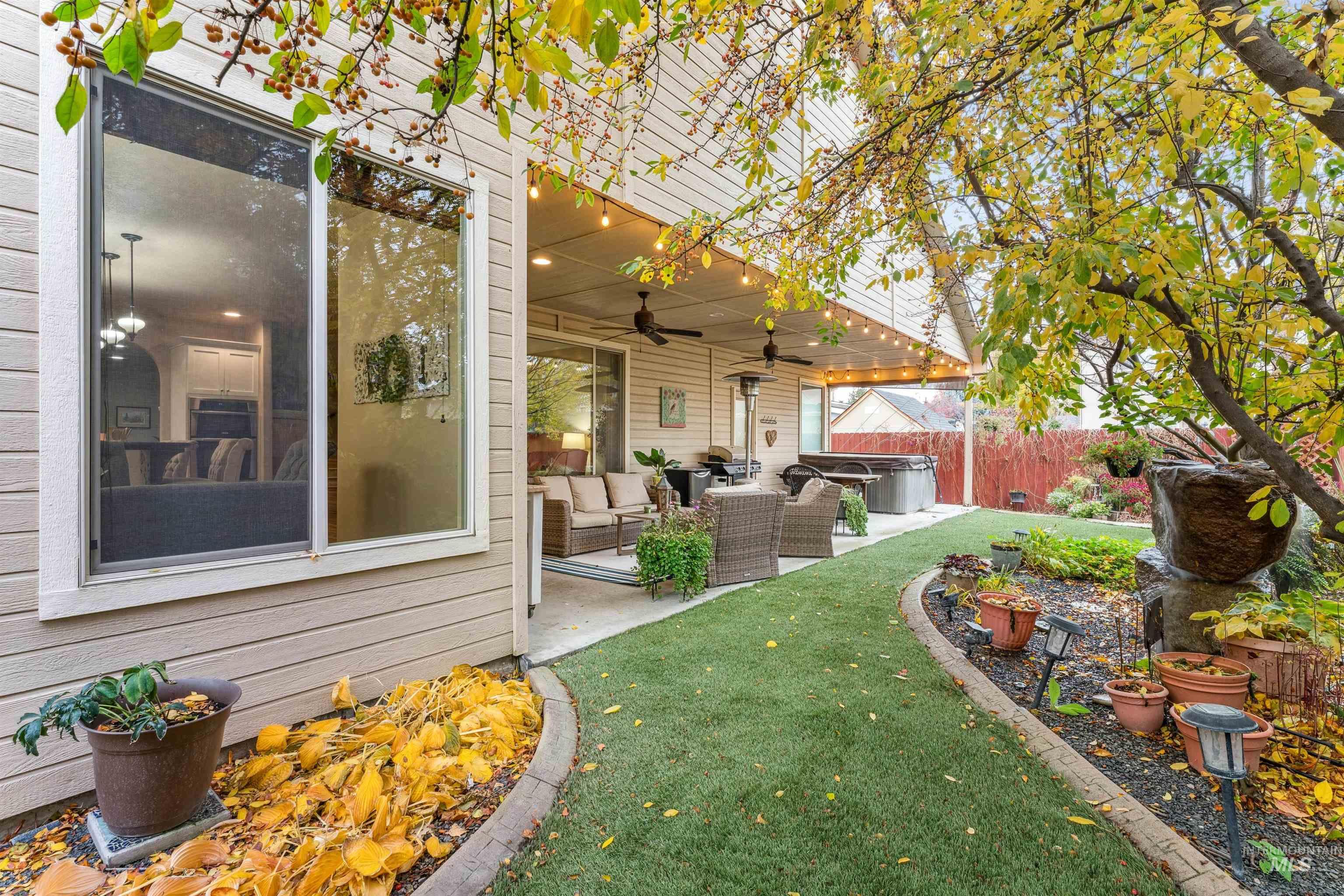 Fenced backyard with an outdoor living space, ceiling fan, a hot tub, and a patio