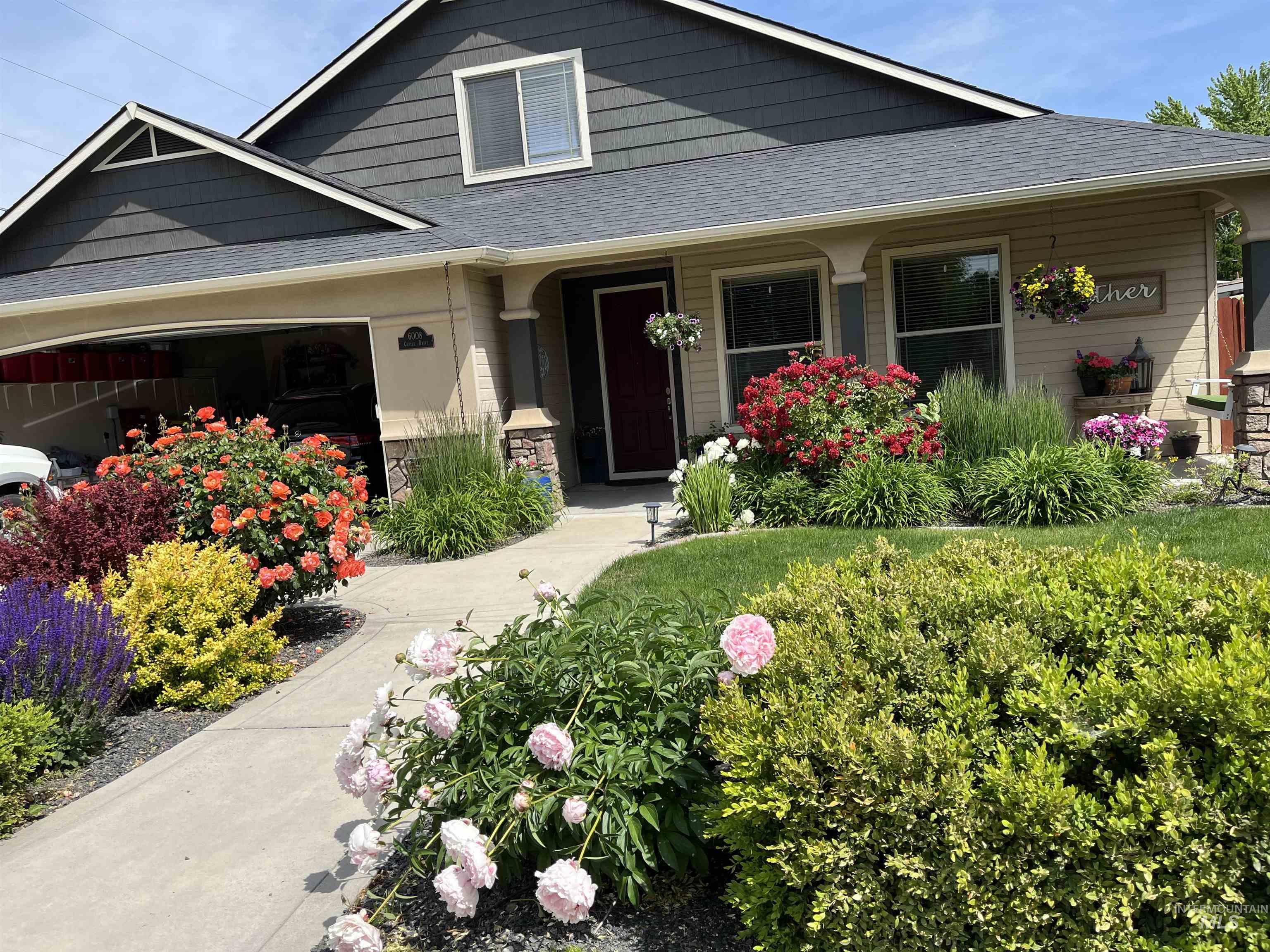 View of front of property featuring a shingled roof, a porch, a garage, and stone siding