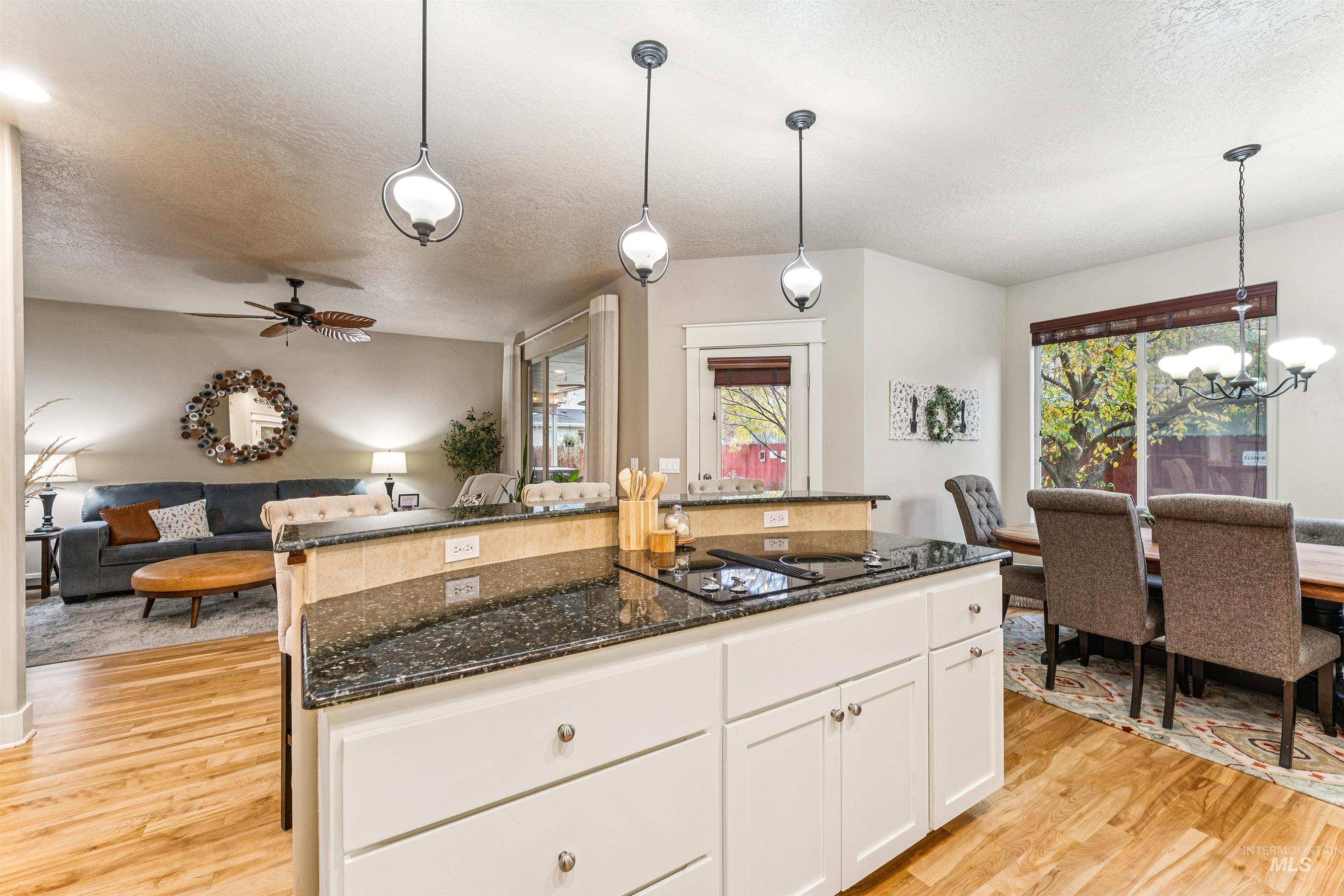 Kitchen featuring white cabinetry, a textured ceiling, dark stone counters, pendant lighting, and a chandelier
