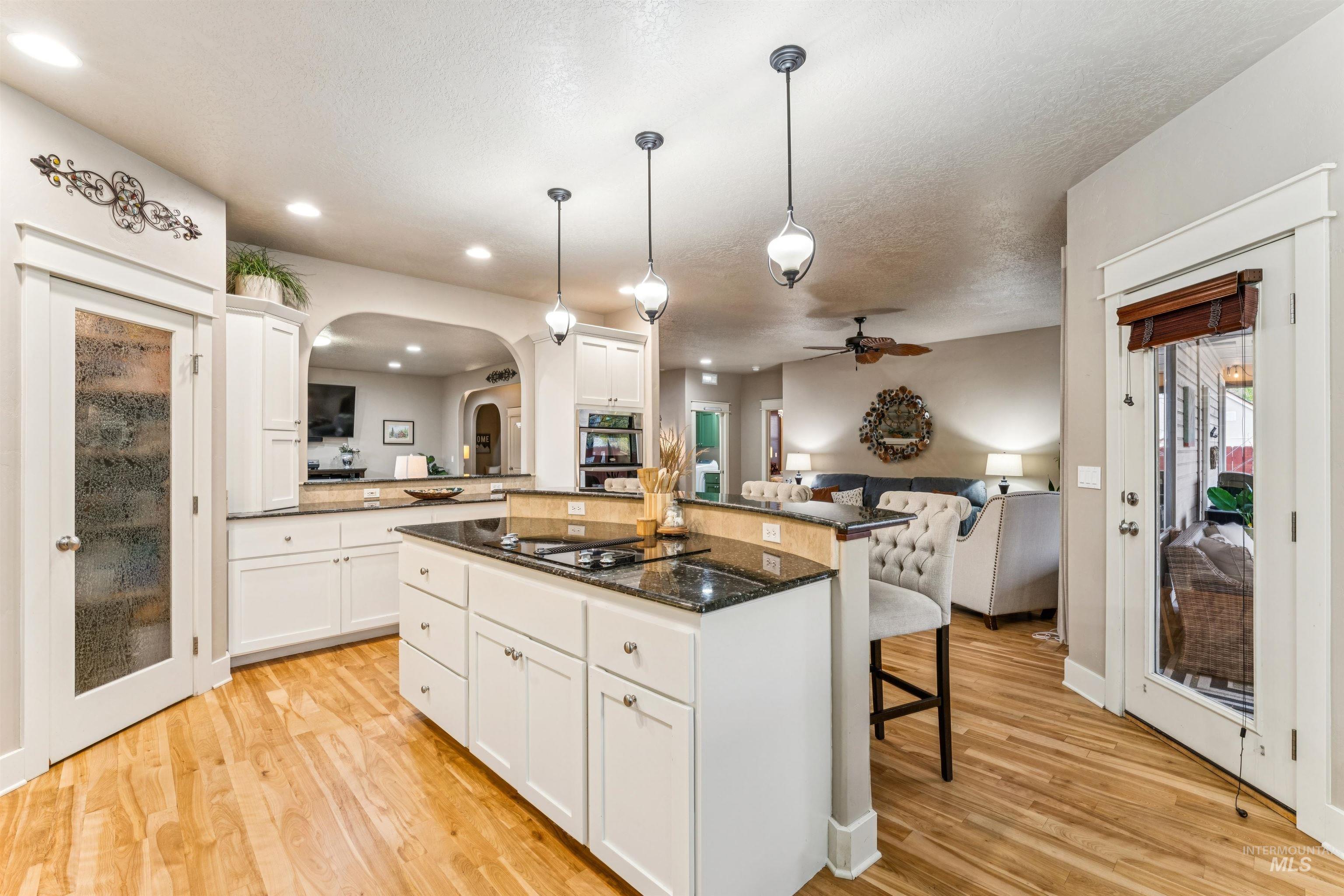 Kitchen with white cabinets, open floor plan, a breakfast bar area, pendant lighting, and dark stone countertops