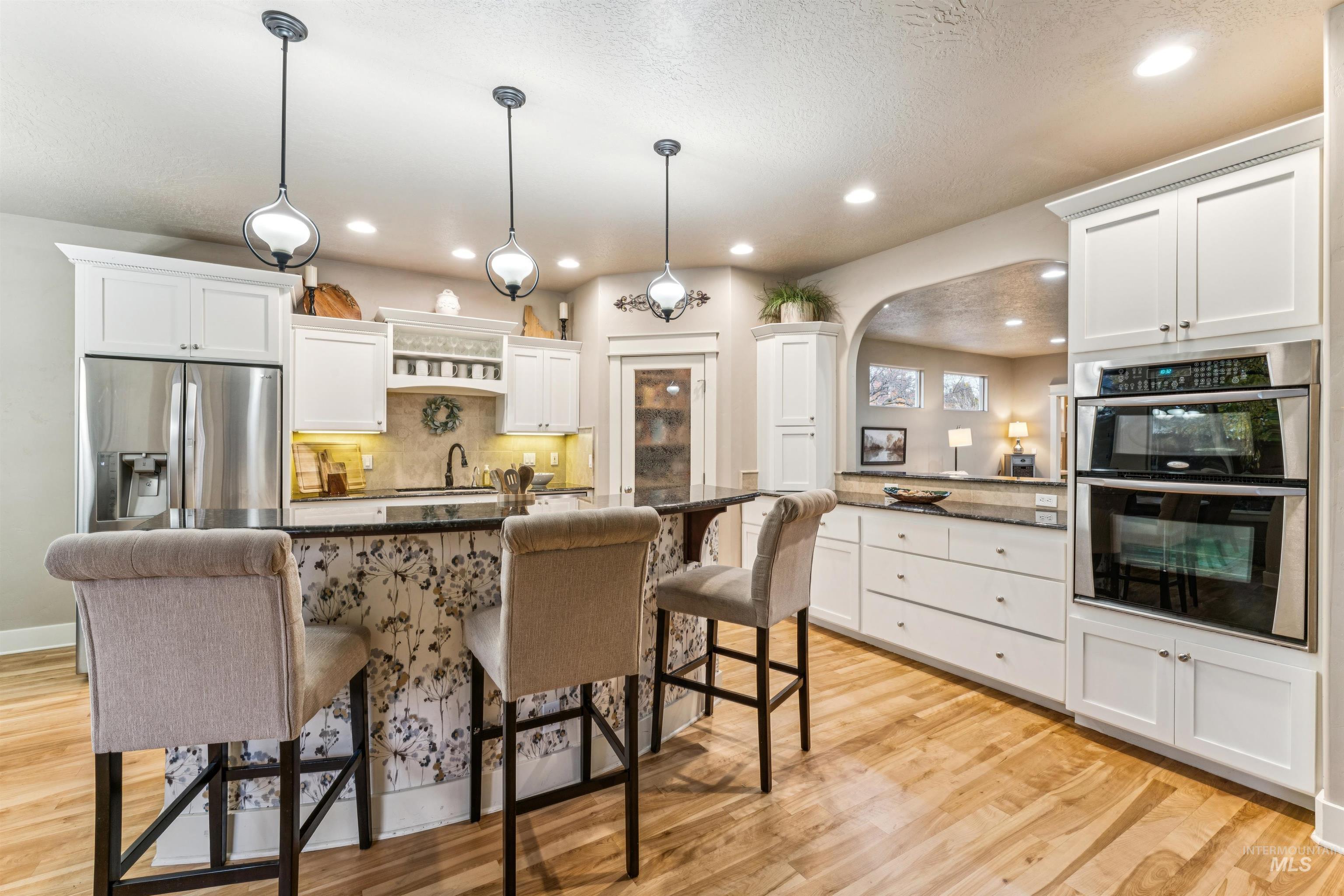 Kitchen featuring a kitchen breakfast bar, white cabinets, pendant lighting, appliances with stainless steel finishes, and recessed lighting