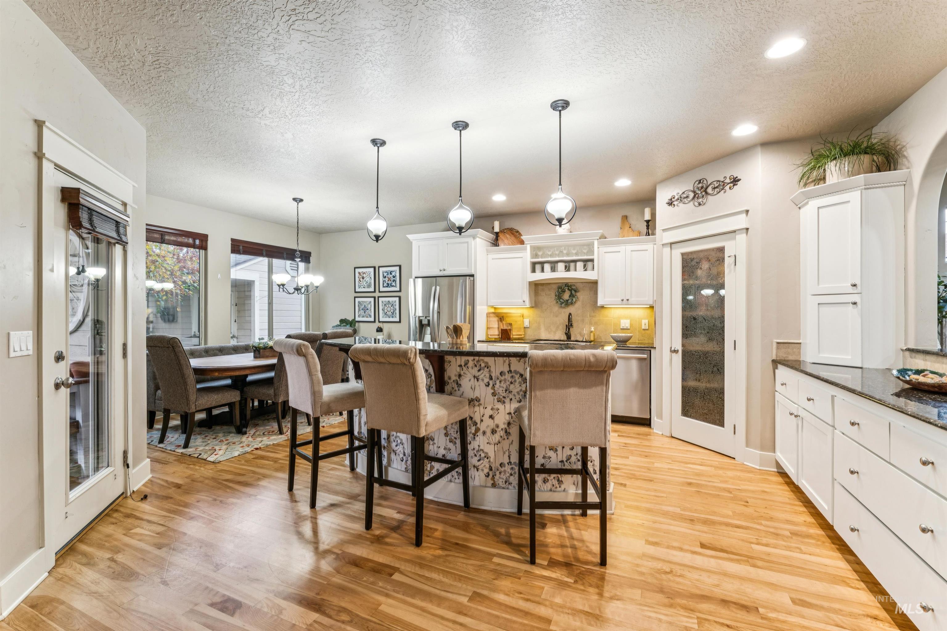 Kitchen featuring white cabinetry, backsplash, a chandelier, a textured ceiling, and a kitchen breakfast bar
