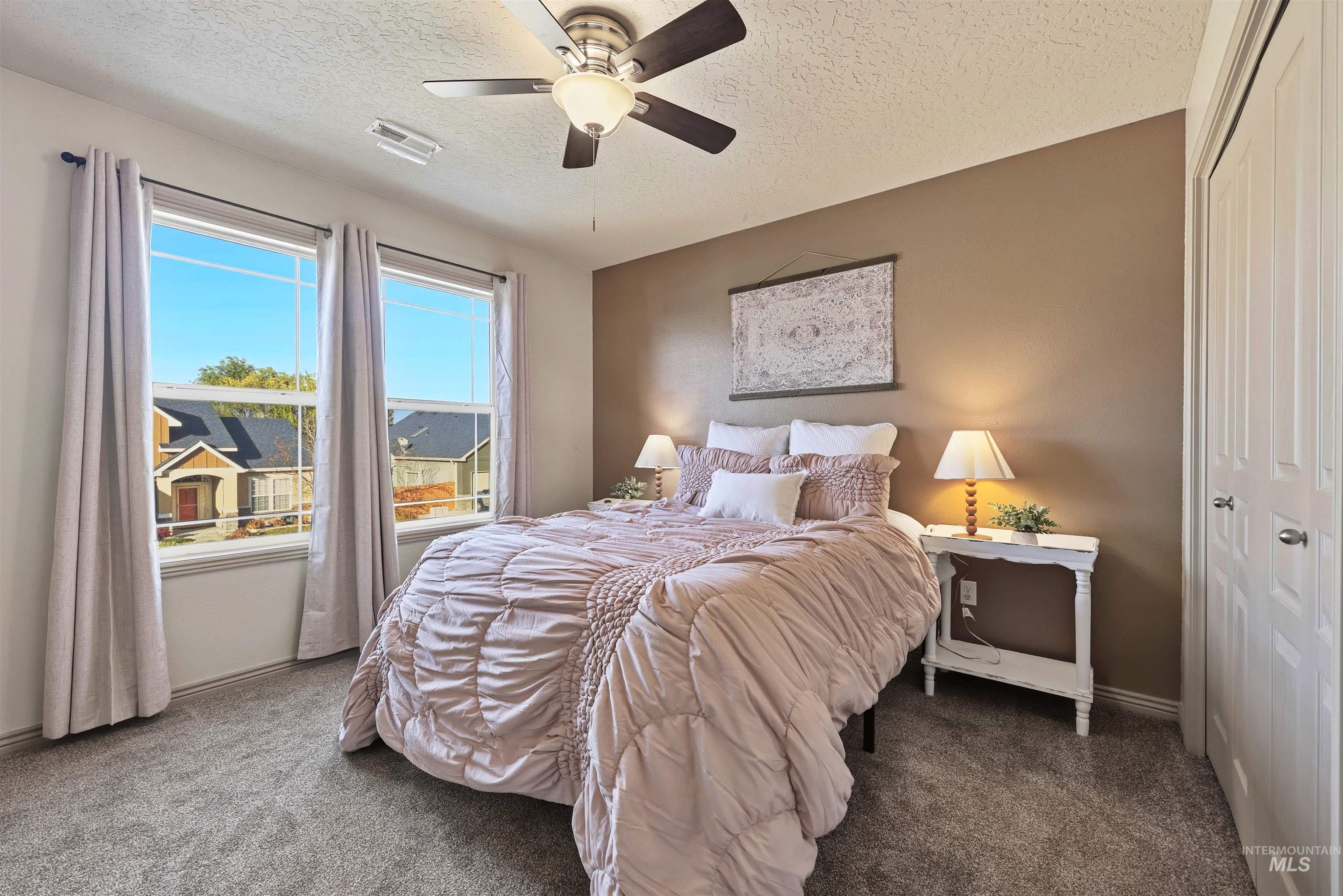 Bedroom with a closet, carpet flooring, a ceiling fan, and a textured ceiling