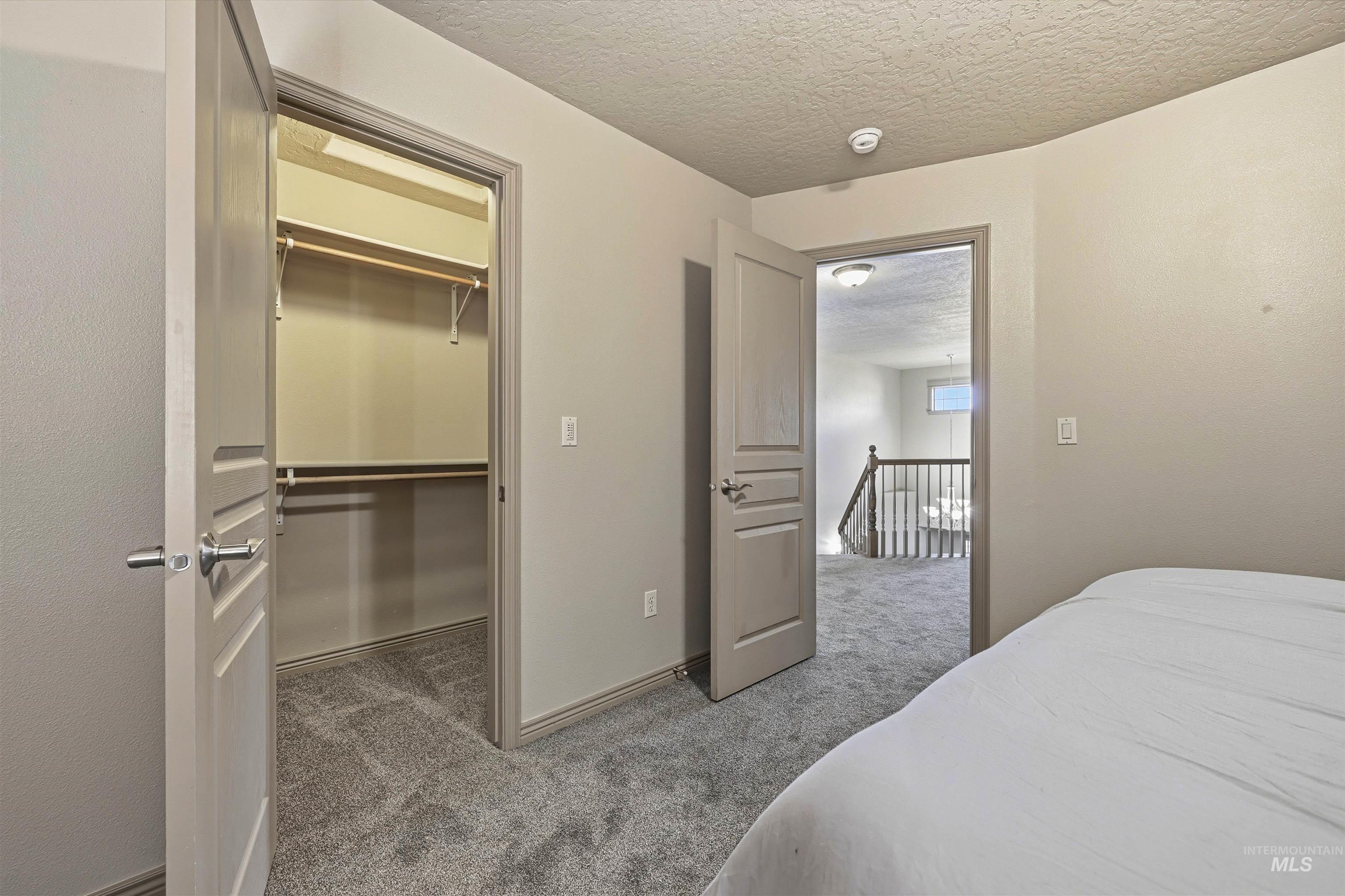 Bedroom featuring a textured ceiling, light carpet, and a spacious closet