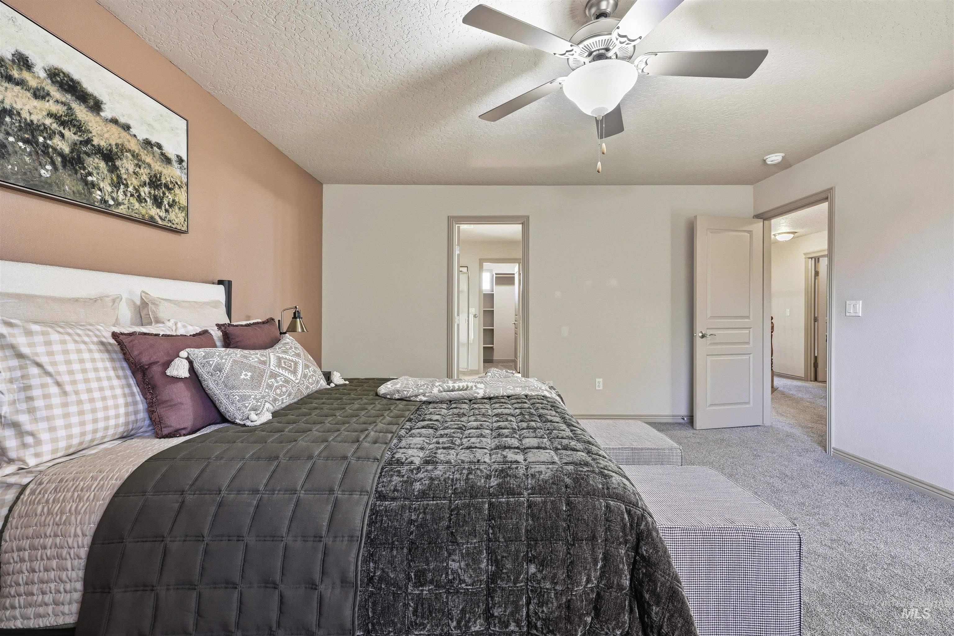 Carpeted bedroom featuring a textured ceiling and a ceiling fan
