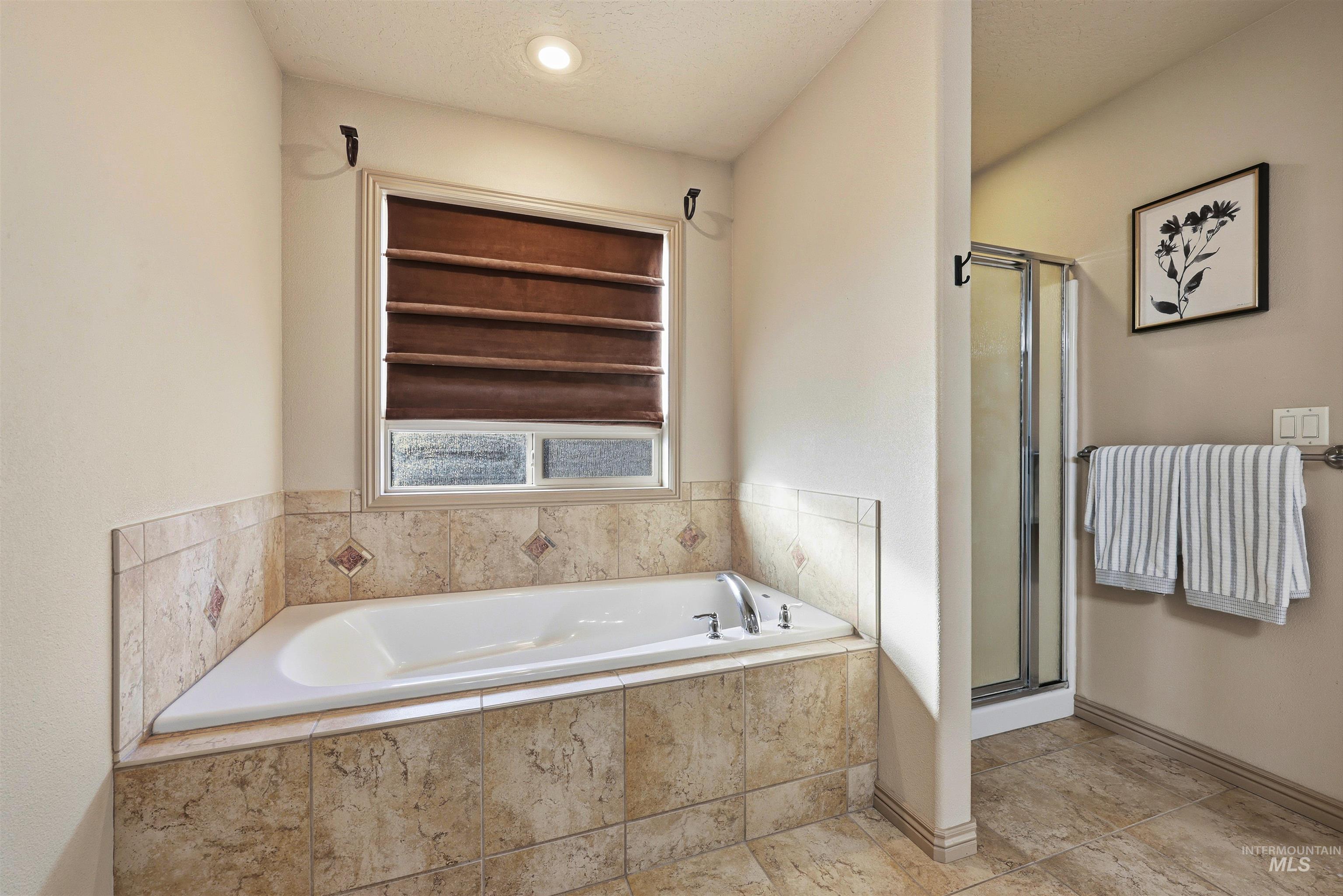 Full bathroom featuring a stall shower, a bath, and a textured ceiling