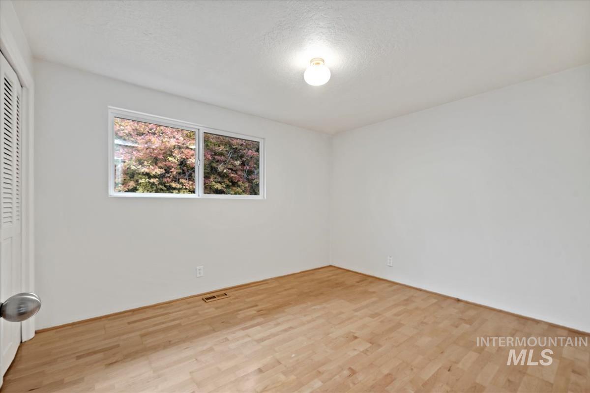 Unfurnished bedroom with light wood finished floors, a textured ceiling, and a closet