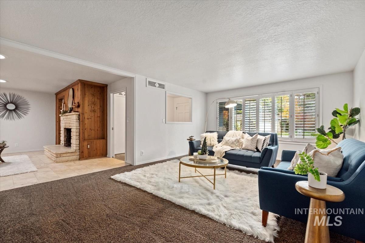 Living room featuring carpet floors, tile patterned flooring, a textured ceiling, and a fireplace