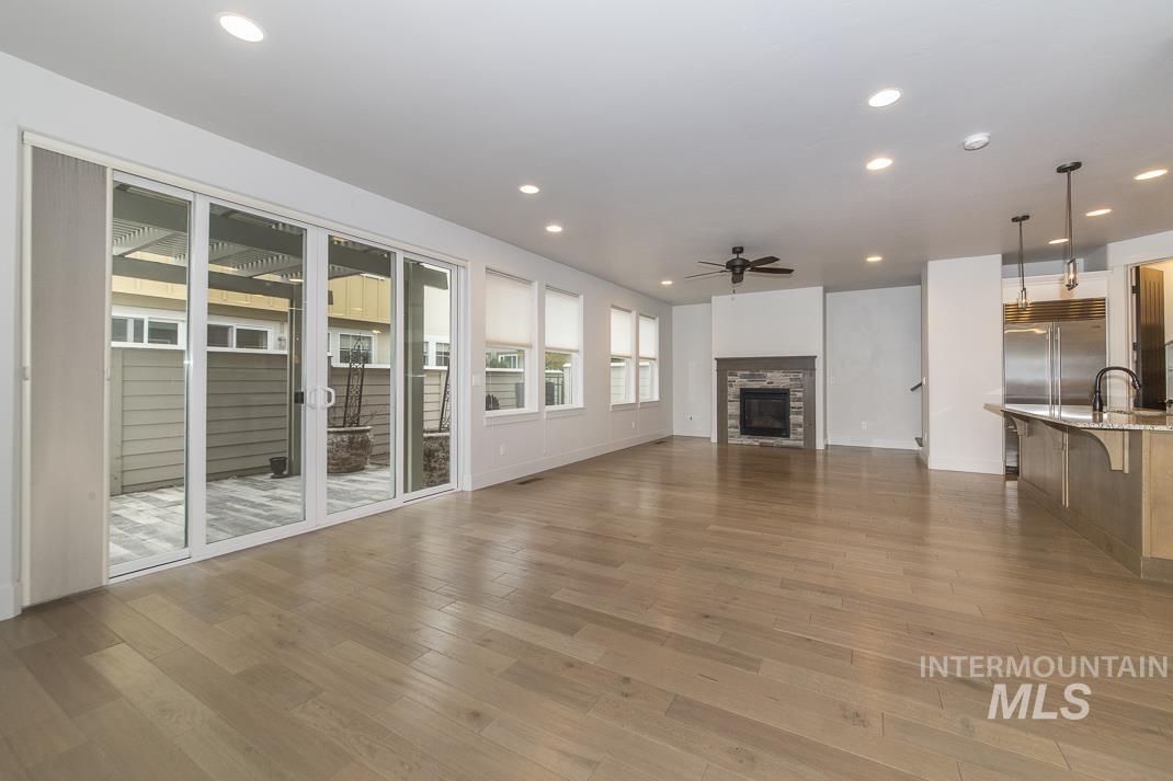Unfurnished living room featuring recessed lighting, ceiling fan, a stone fireplace, and dark wood finished floors