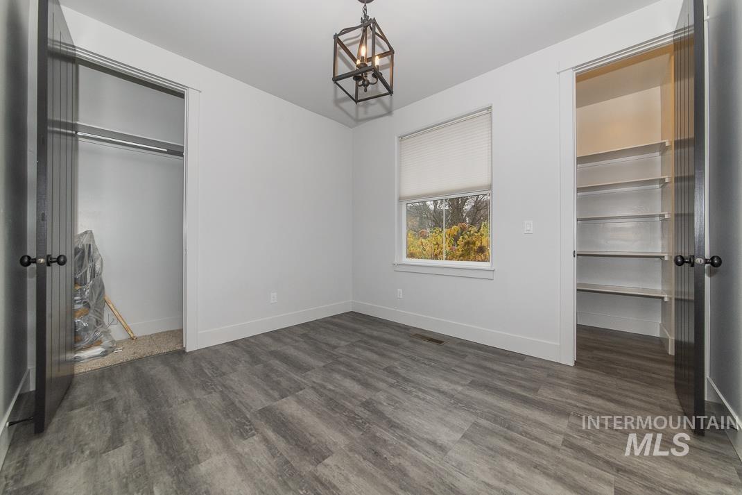 Unfurnished bedroom featuring wood finished floors, a chandelier, and a walk in closet