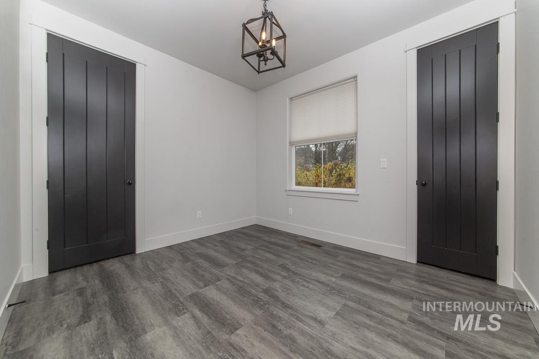 Unfurnished bedroom with wood finished floors and a chandelier