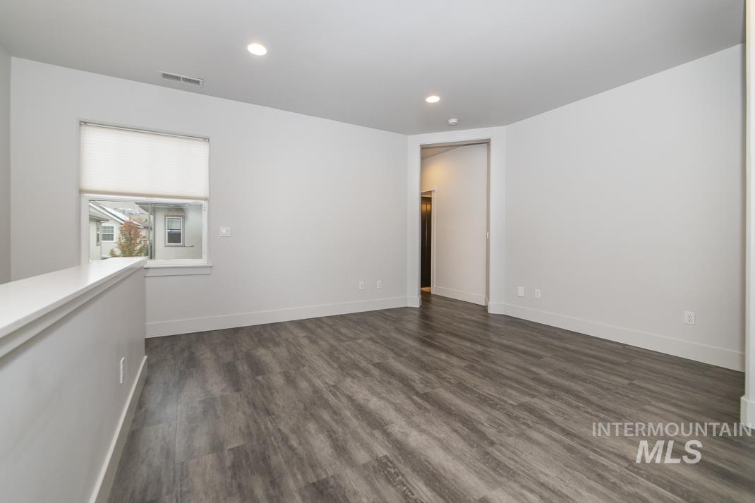 Empty room with dark wood finished floors and recessed lighting