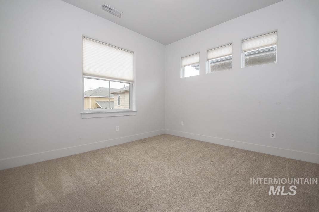 Spare room featuring light carpet and baseboards