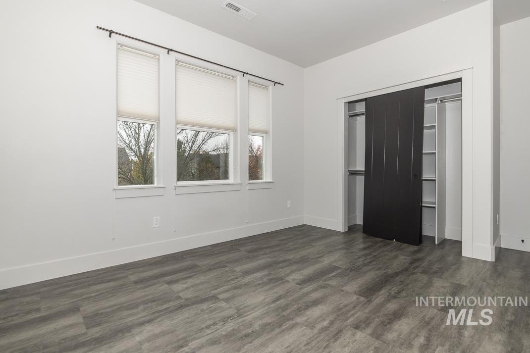 Unfurnished bedroom featuring a closet and dark wood-type flooring