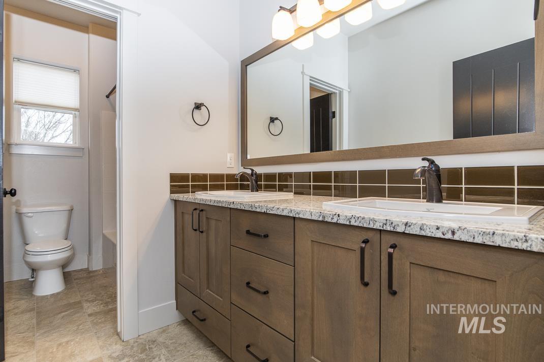 Full bathroom with double vanity, bathing tub / shower combination, and backsplash
