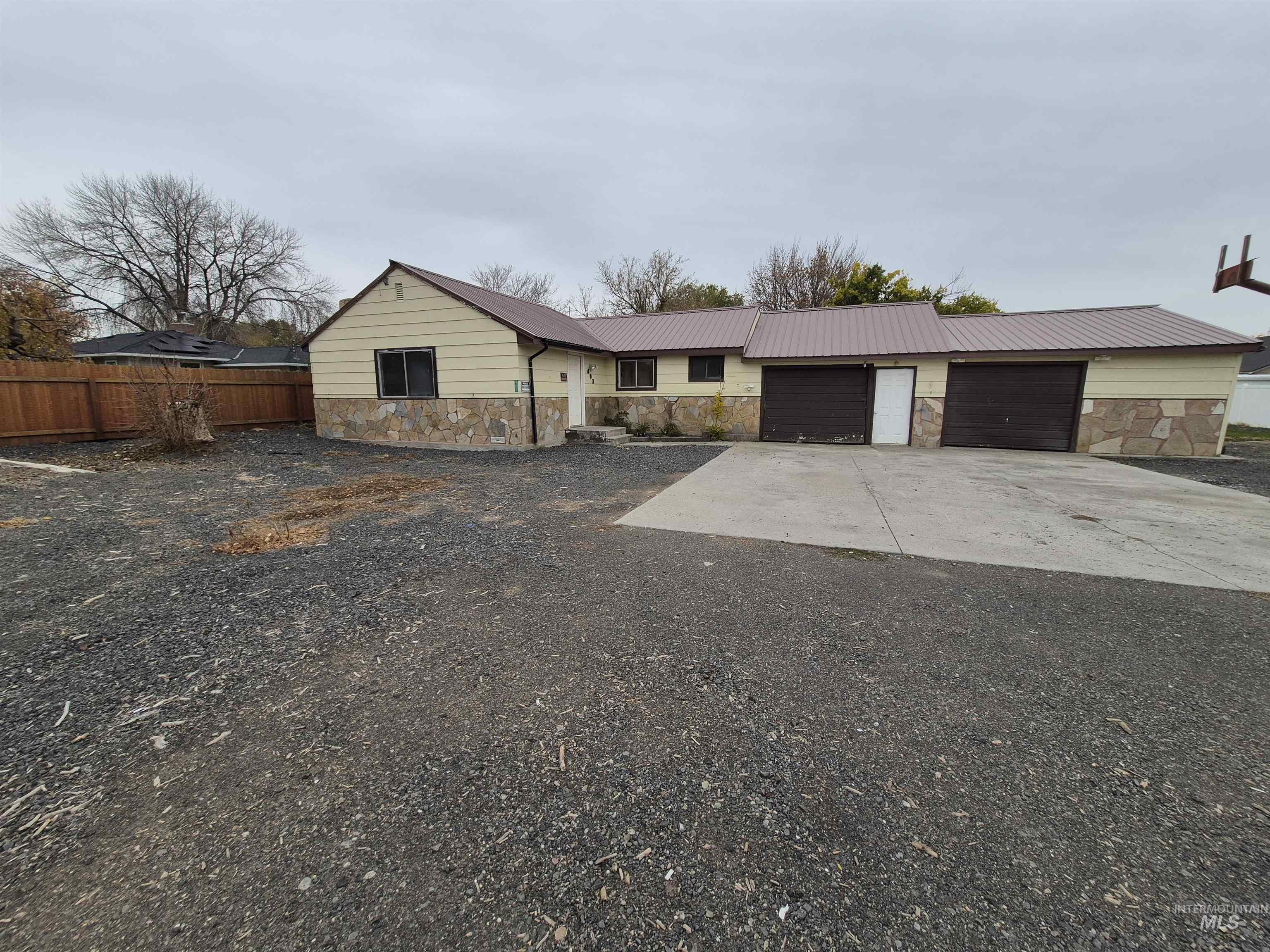 Single story home featuring stone siding, concrete driveway, a metal roof, and an attached garage