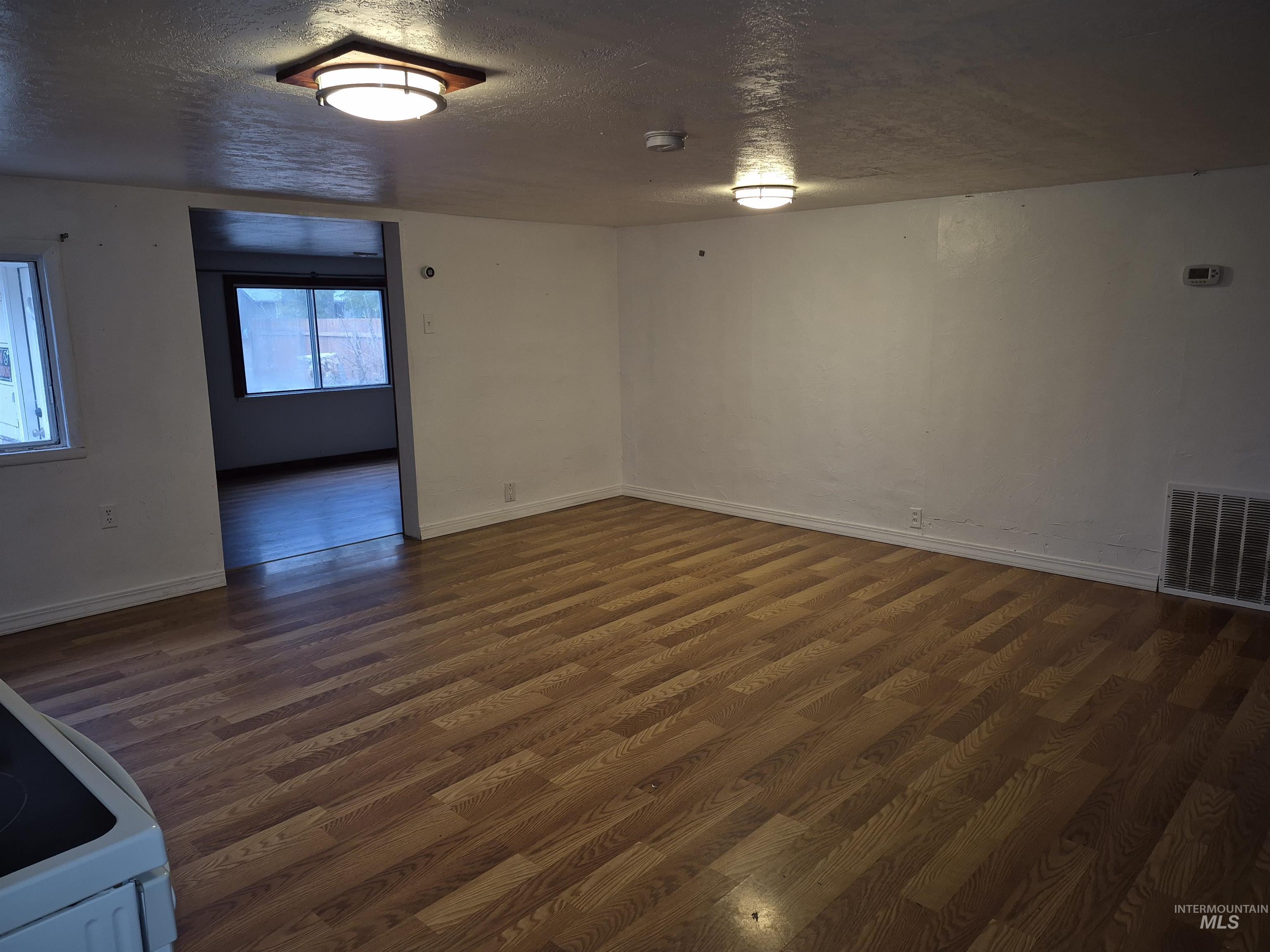 Spare room with a textured ceiling and dark wood-style flooring