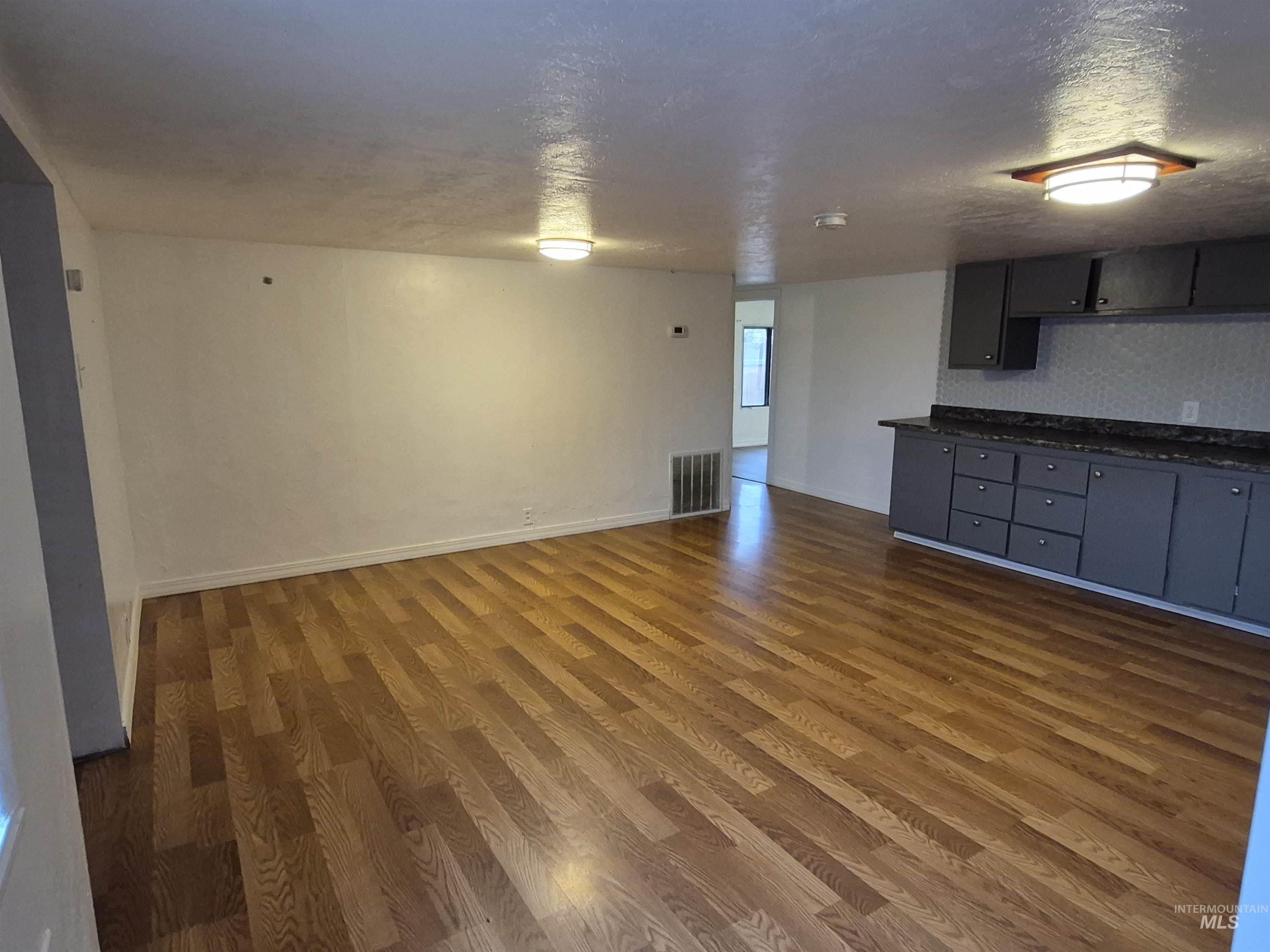 Unfurnished living room featuring a textured ceiling and dark wood-style flooring