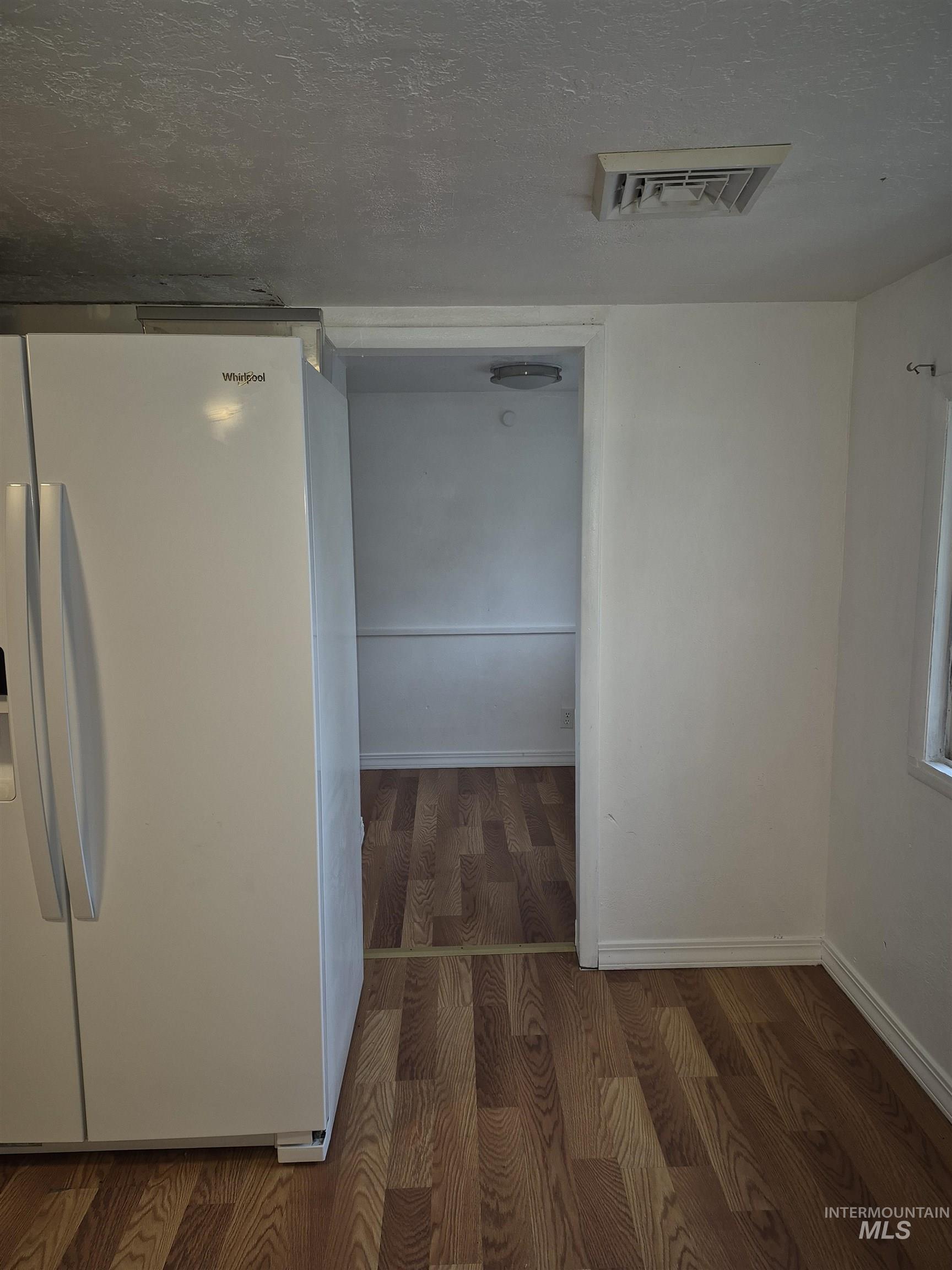 Hallway with a textured ceiling and dark wood finished floors