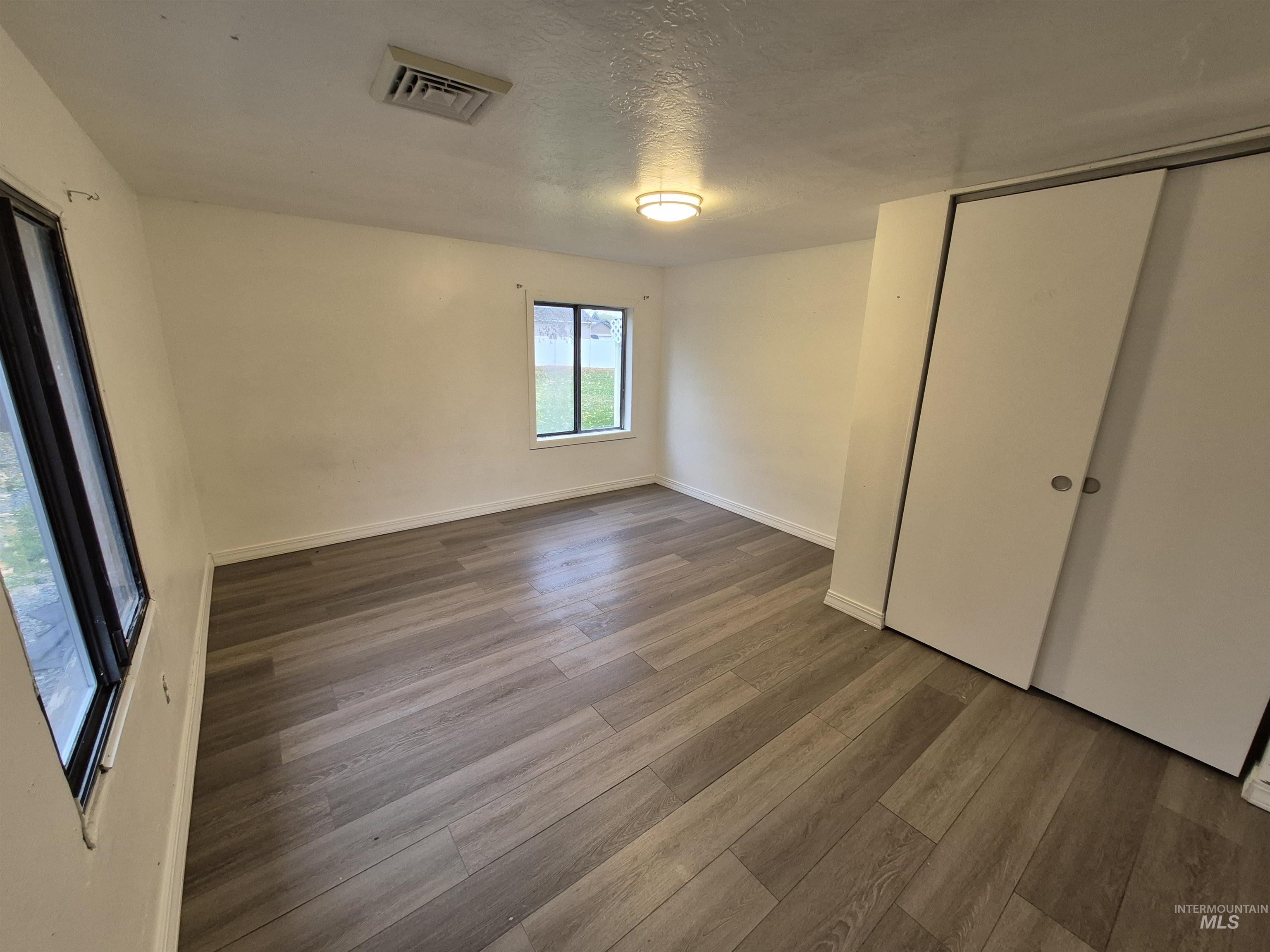 Unfurnished bedroom with a textured ceiling, wood finished floors, and a closet