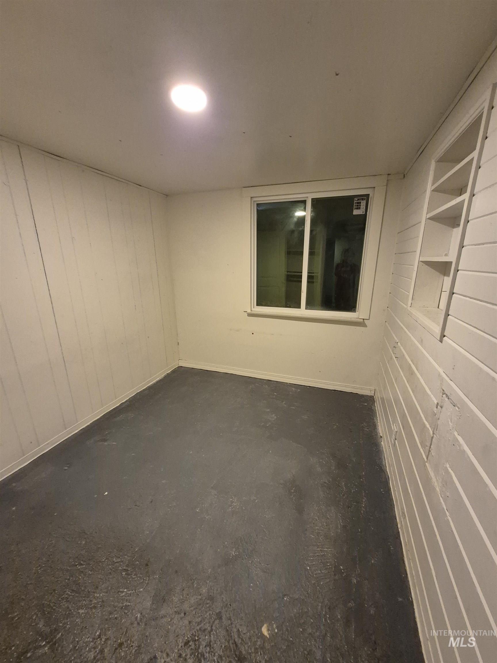 Unfurnished room with unfinished concrete flooring and wooden walls