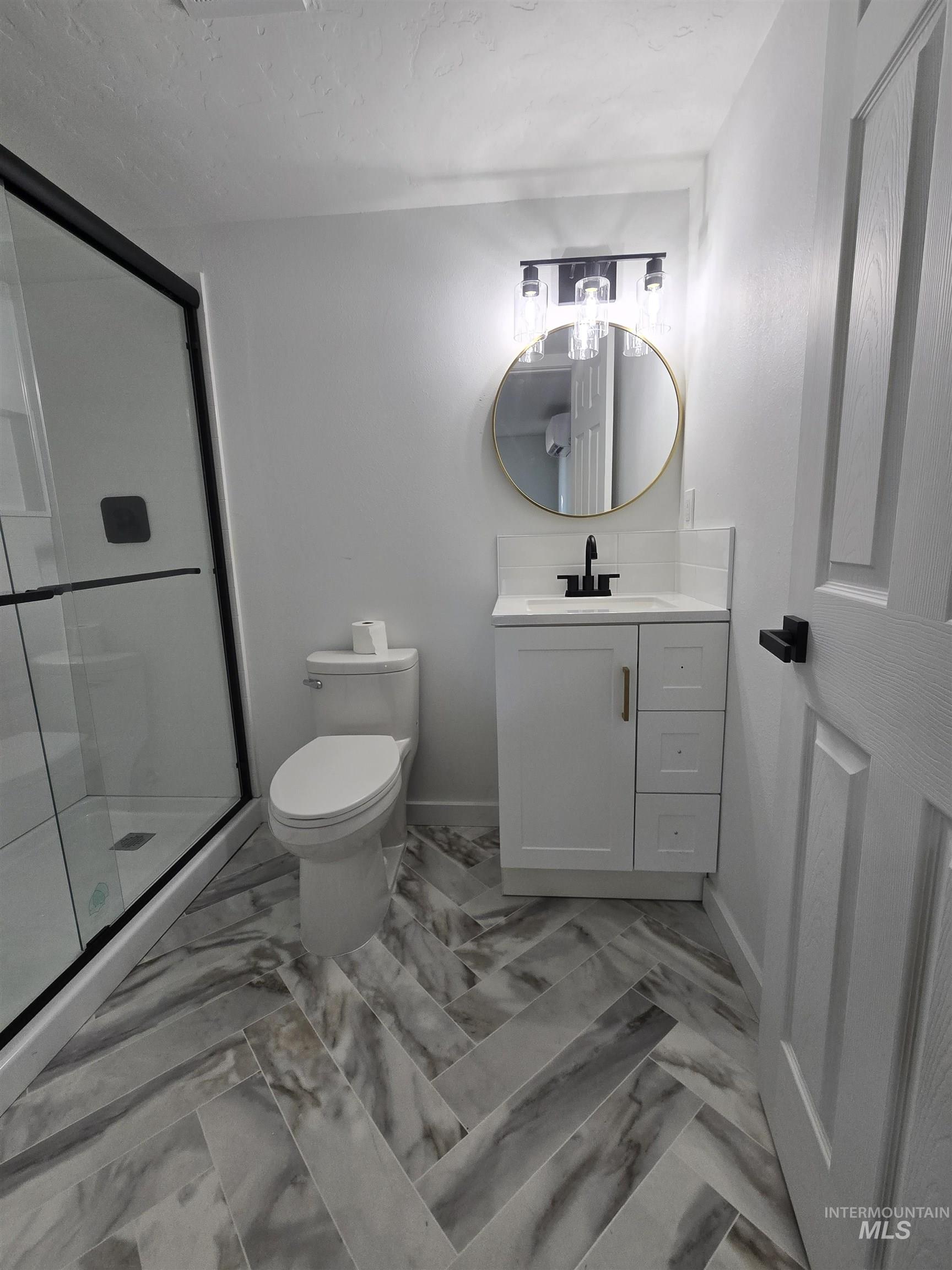 Bathroom featuring vanity, a shower stall, light marble finish floors, and a textured ceiling