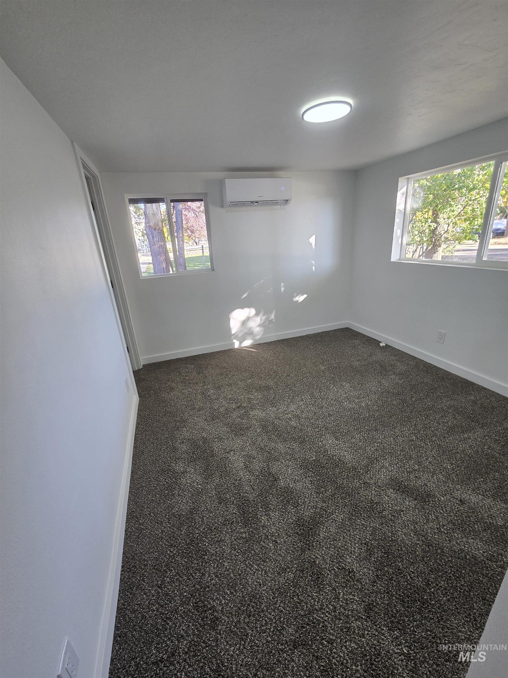 Unfurnished room with dark carpet and baseboards