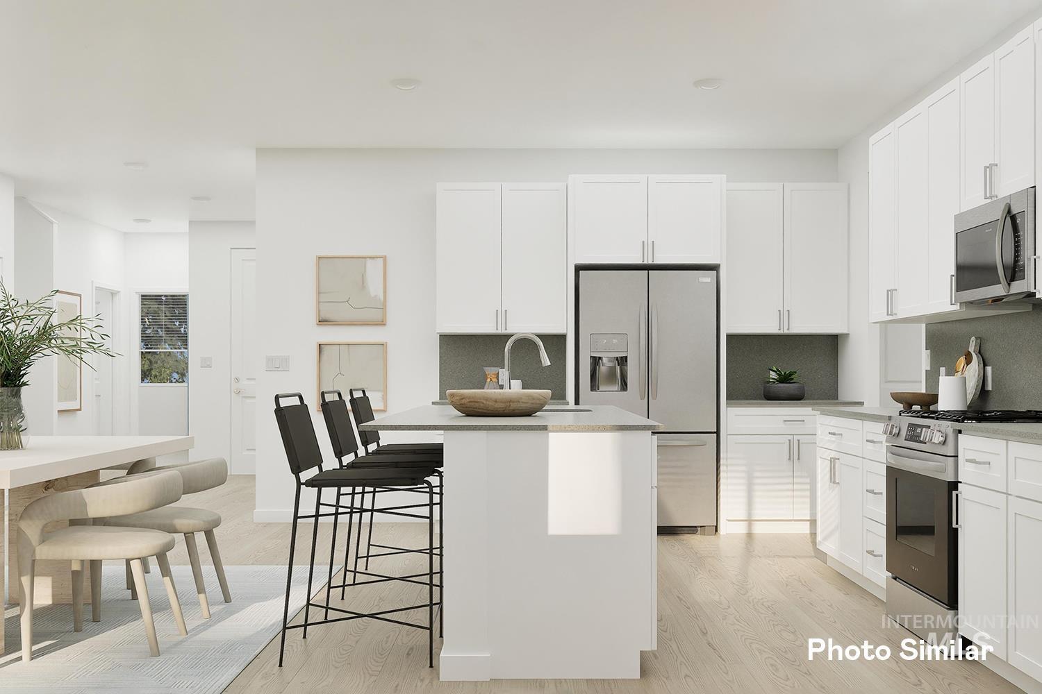 Kitchen with backsplash, stainless steel appliances, light wood-type flooring, and a breakfast bar area