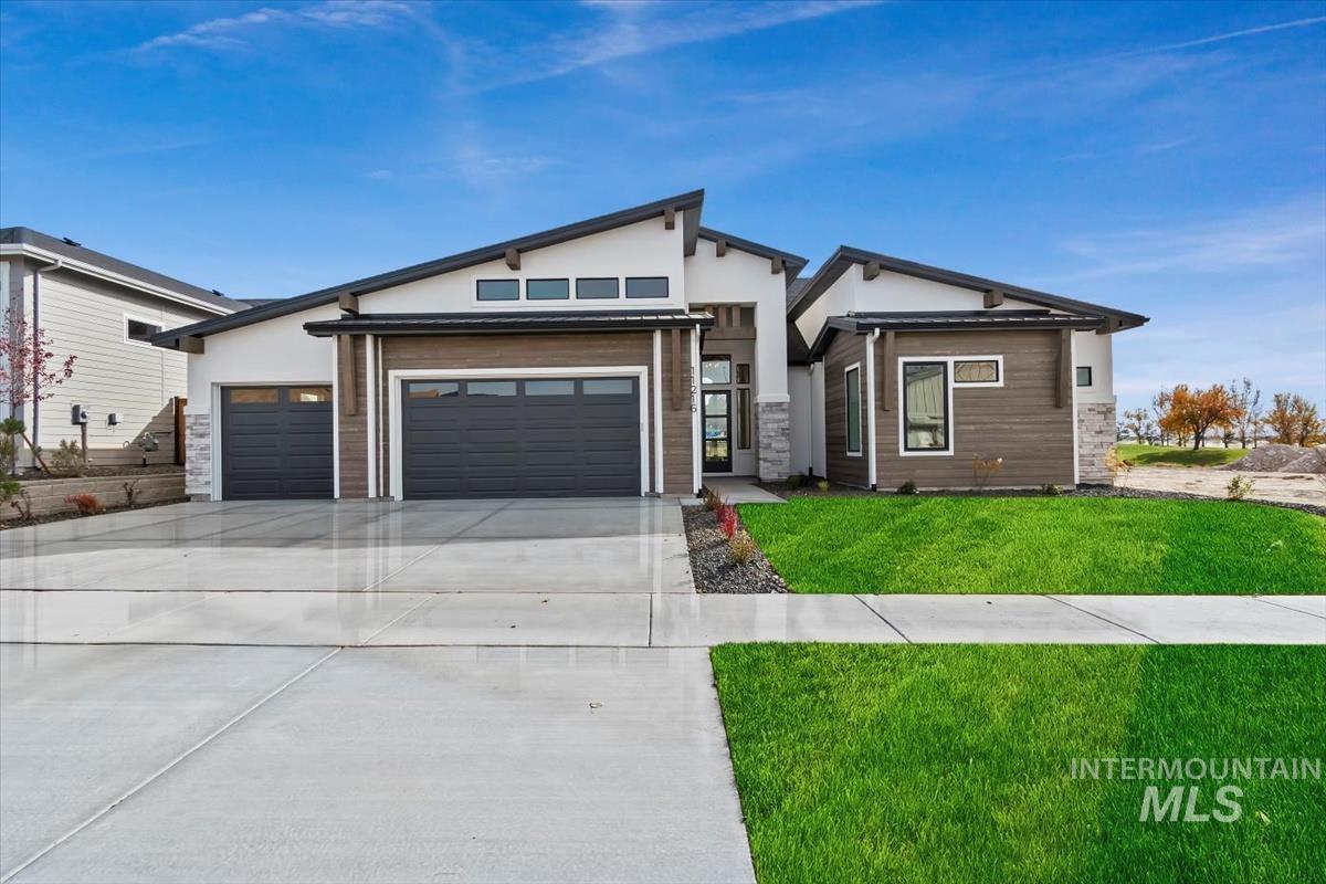 Contemporary home featuring a front lawn, concrete driveway, a garage, stone siding, and stucco siding