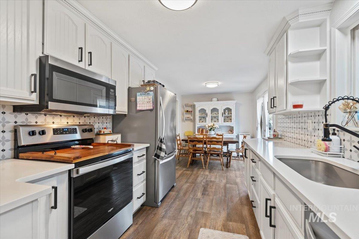 Kitchen with tasteful backsplash, stainless steel appliances, and white cabinets