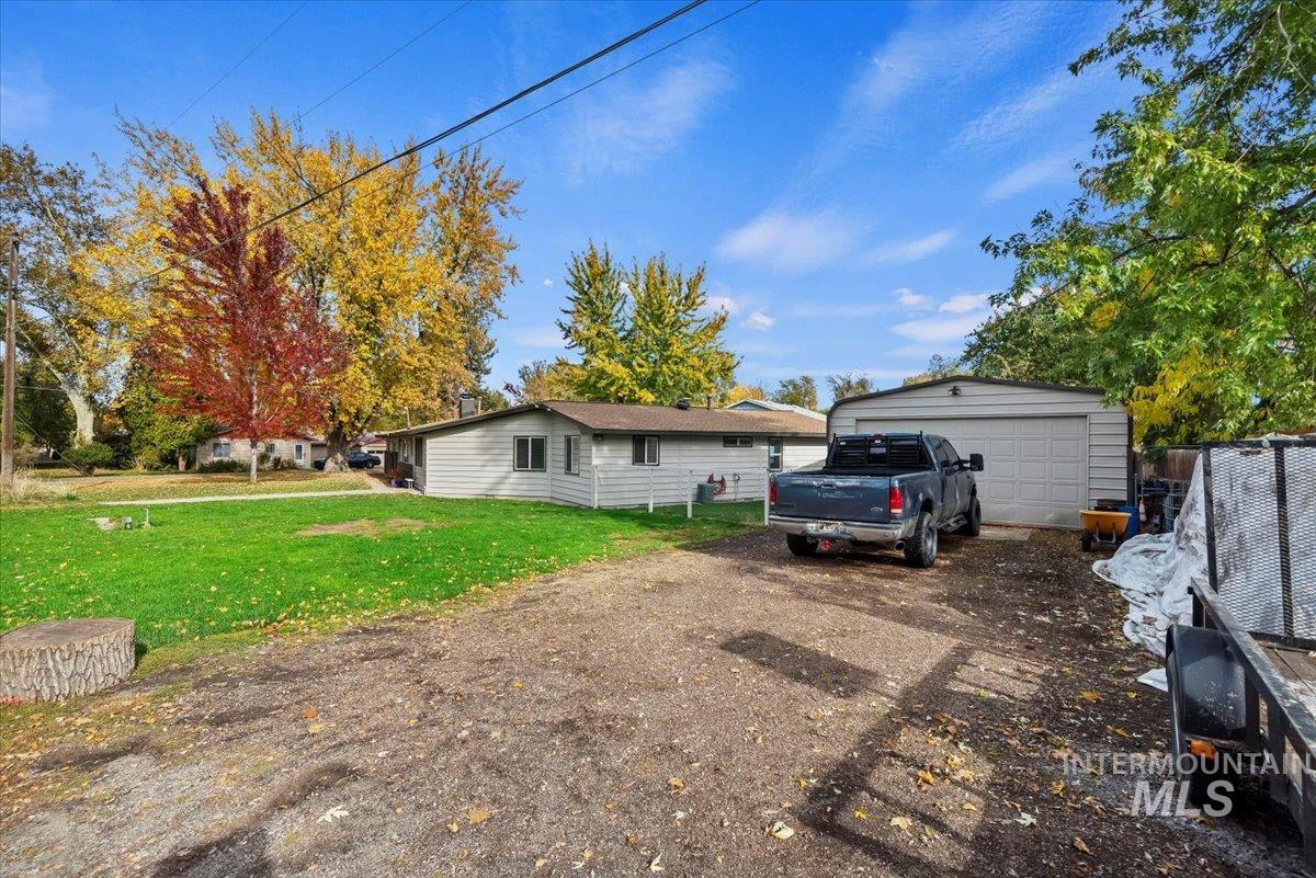 View of home's exterior with a lawn, a detached garage, and an outdoor structure