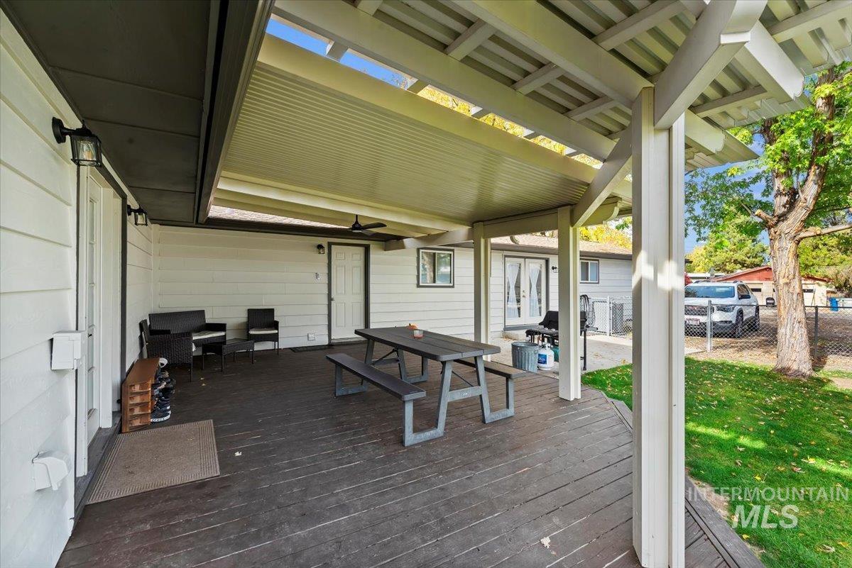 Wooden terrace featuring outdoor dining area, a ceiling fan, and french doors