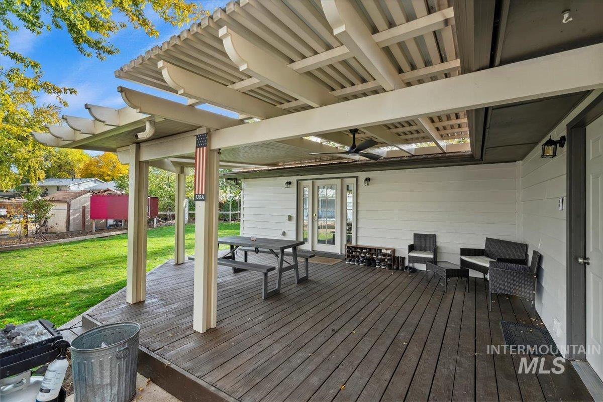 Wooden terrace featuring a yard, outdoor dining area, and ceiling fan