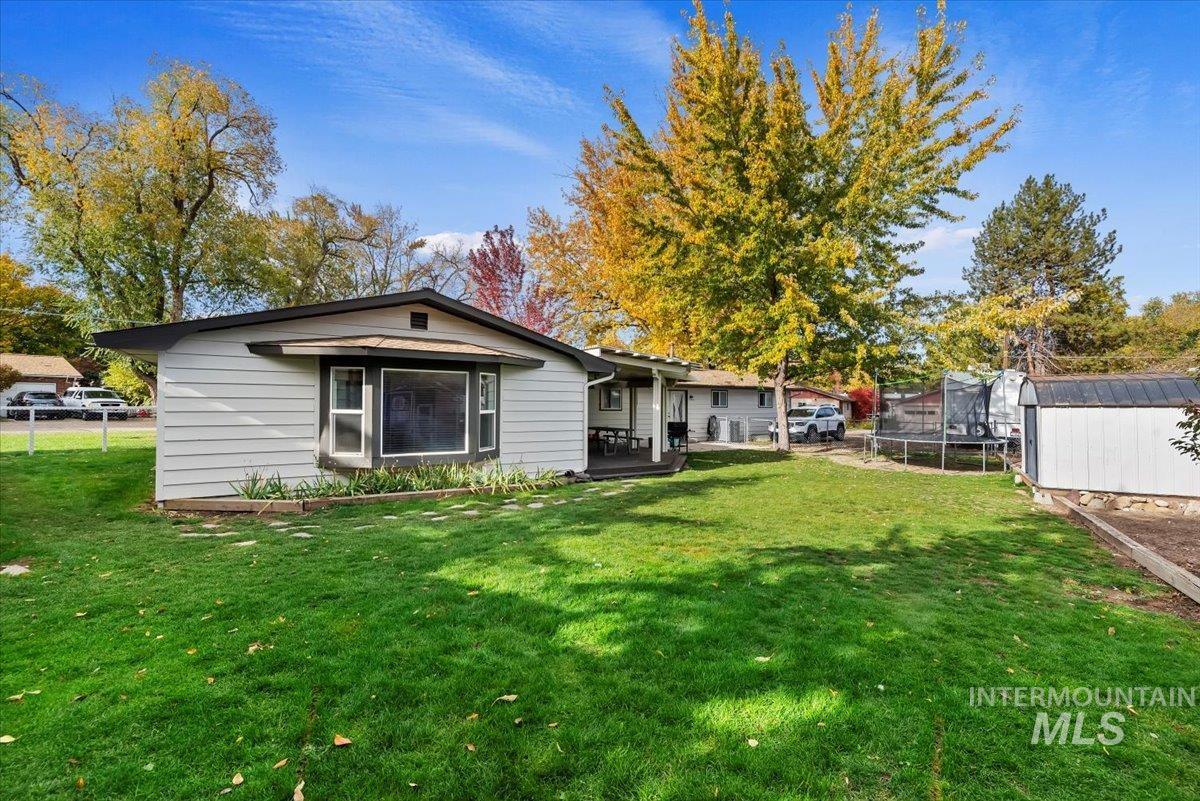 Rear view of house featuring a trampoline and a storage shed