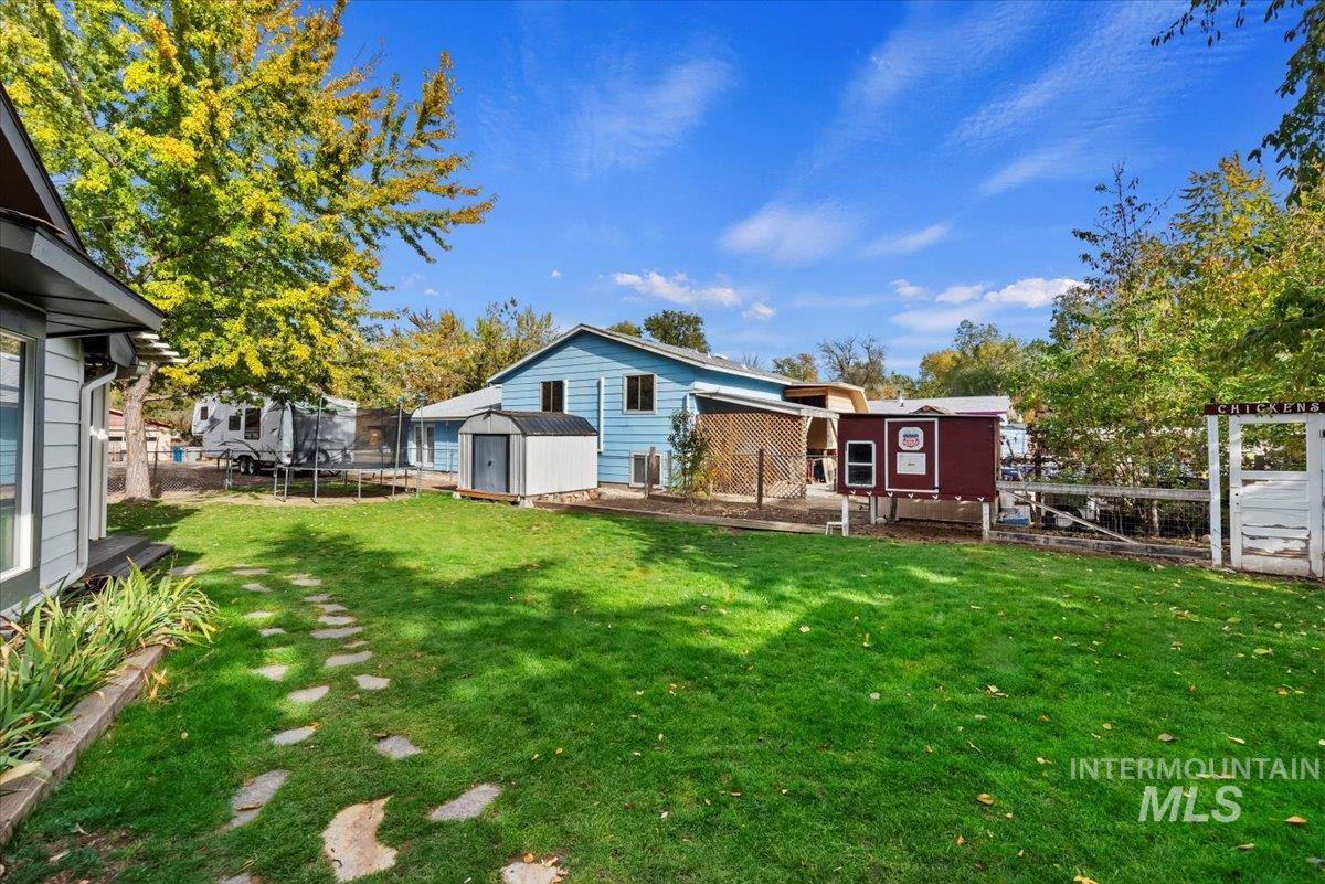 Rear view of property featuring a trampoline, exterior structure, and a storage shed