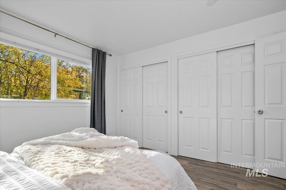 Bedroom with multiple closets and dark wood-style floors