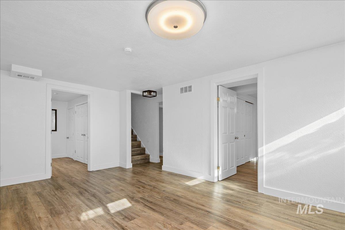 Empty room with light wood-type flooring, stairs, and a textured ceiling