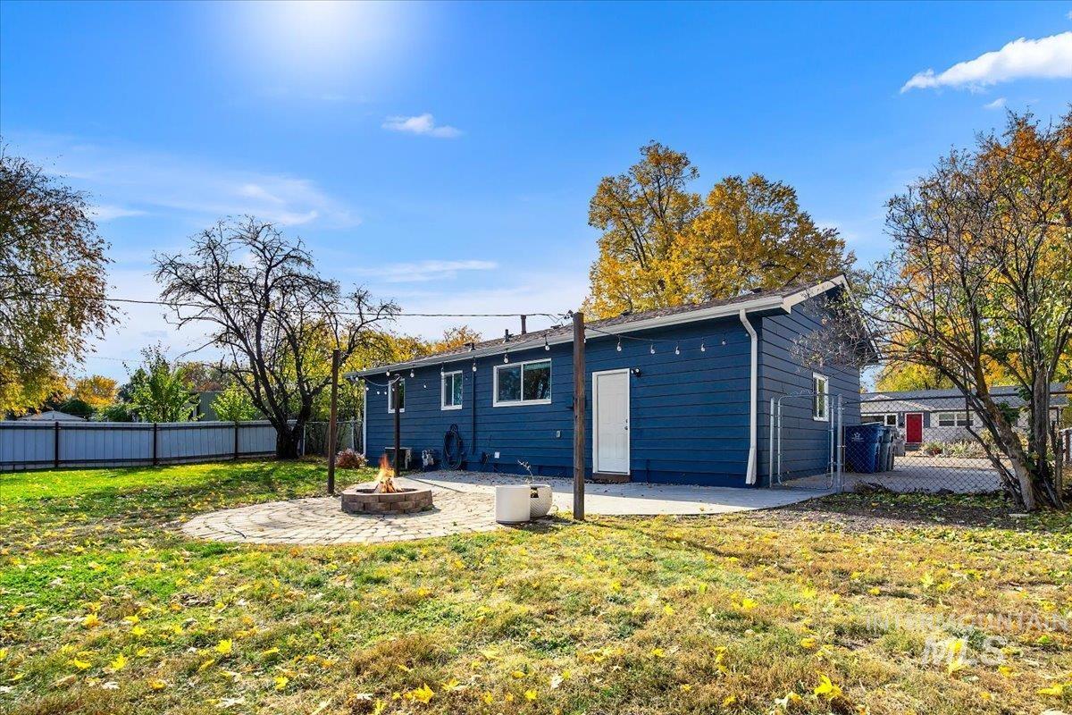 Rear view of house with a fenced backyard, a fire pit, and a patio