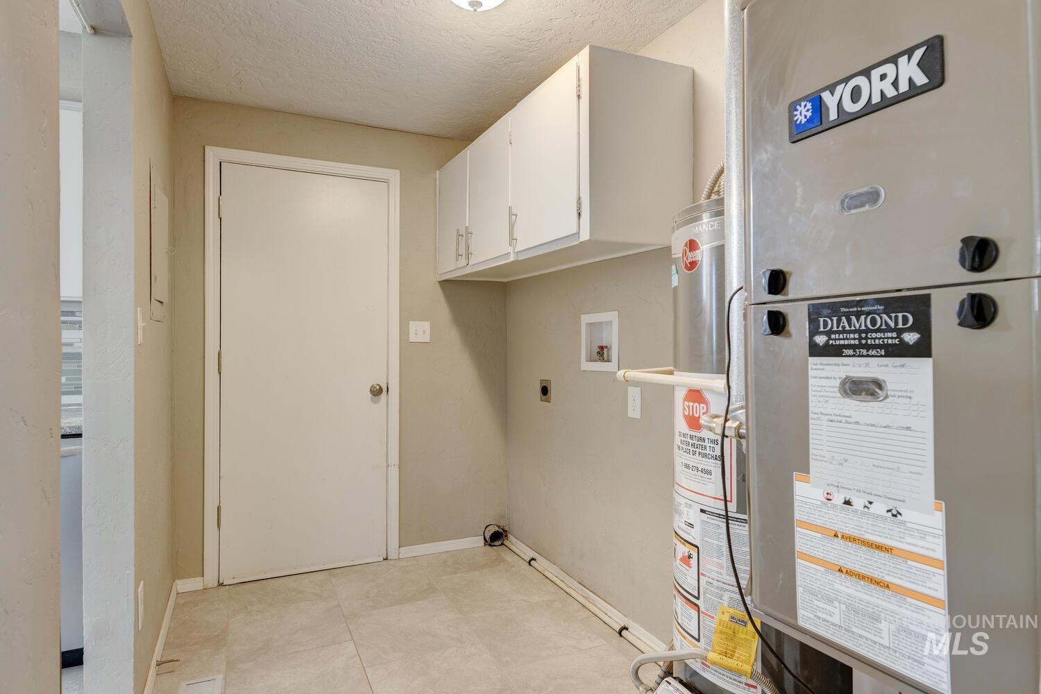 Laundry area featuring heating unit, cabinet space, a textured ceiling, electric dryer hookup, and hookup for a washing machine