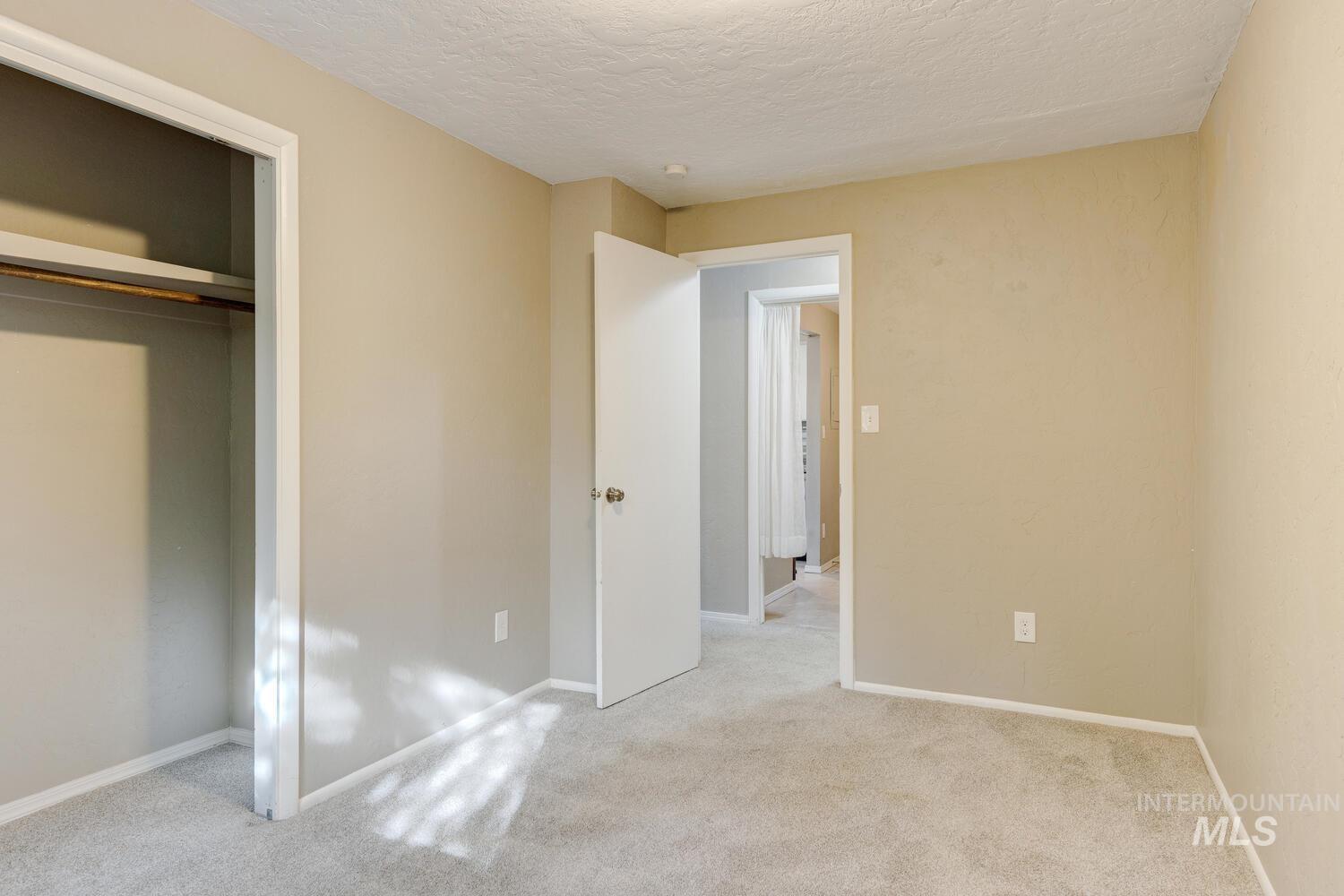 Unfurnished bedroom with light colored carpet, a textured ceiling, and a closet