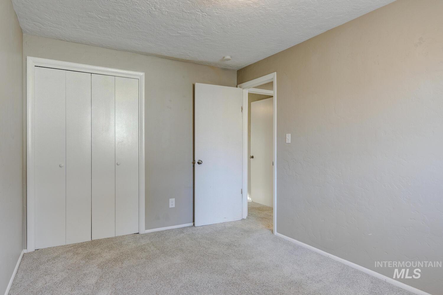Unfurnished bedroom featuring carpet, a textured ceiling, and a closet