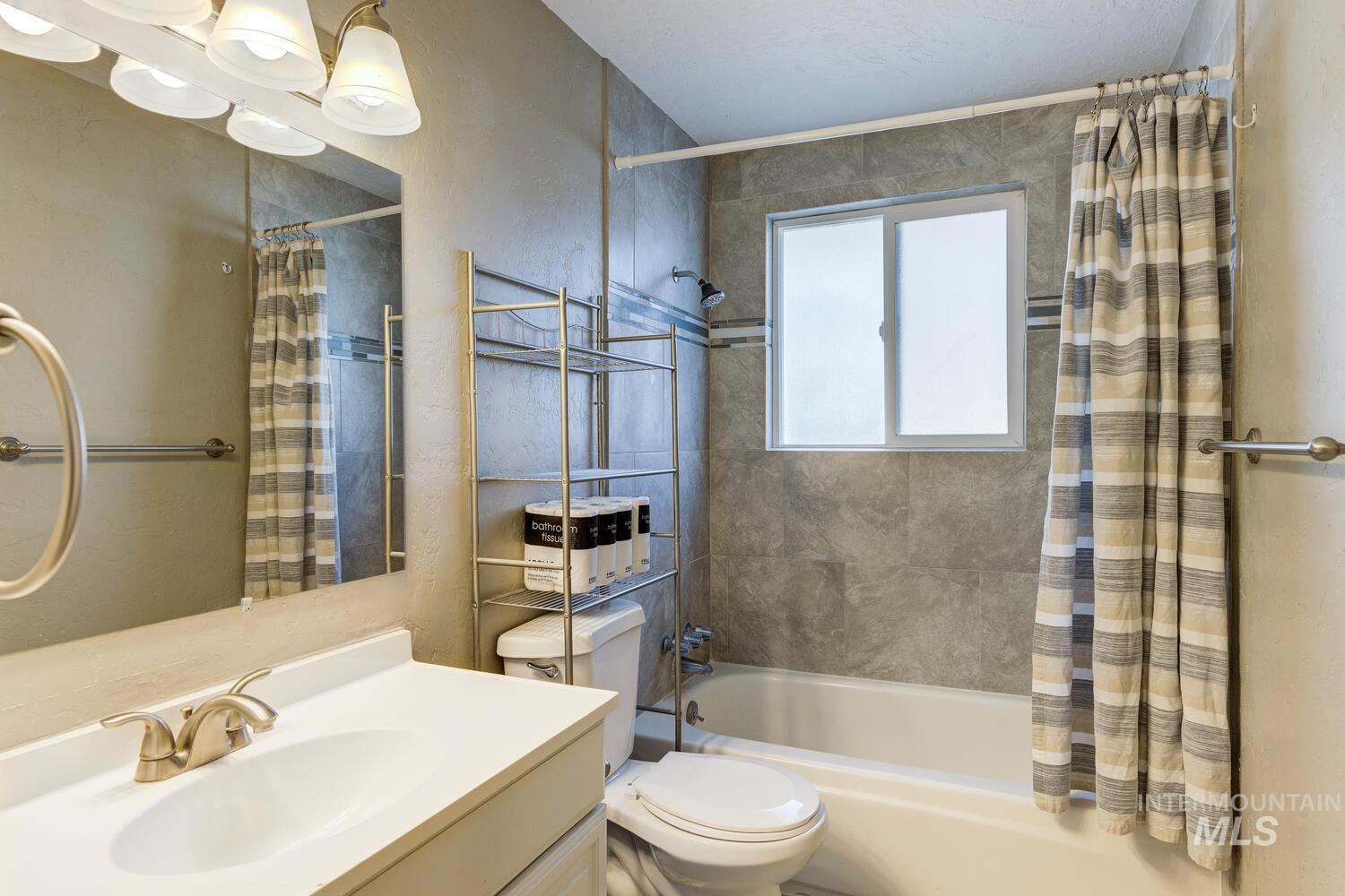 Bathroom with shower / bath combo with shower curtain, vanity, and a textured wall