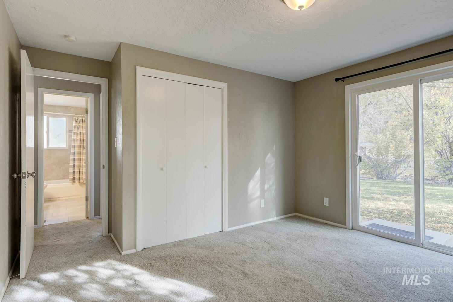 Unfurnished bedroom featuring carpet floors, access to exterior, a closet, and a textured ceiling
