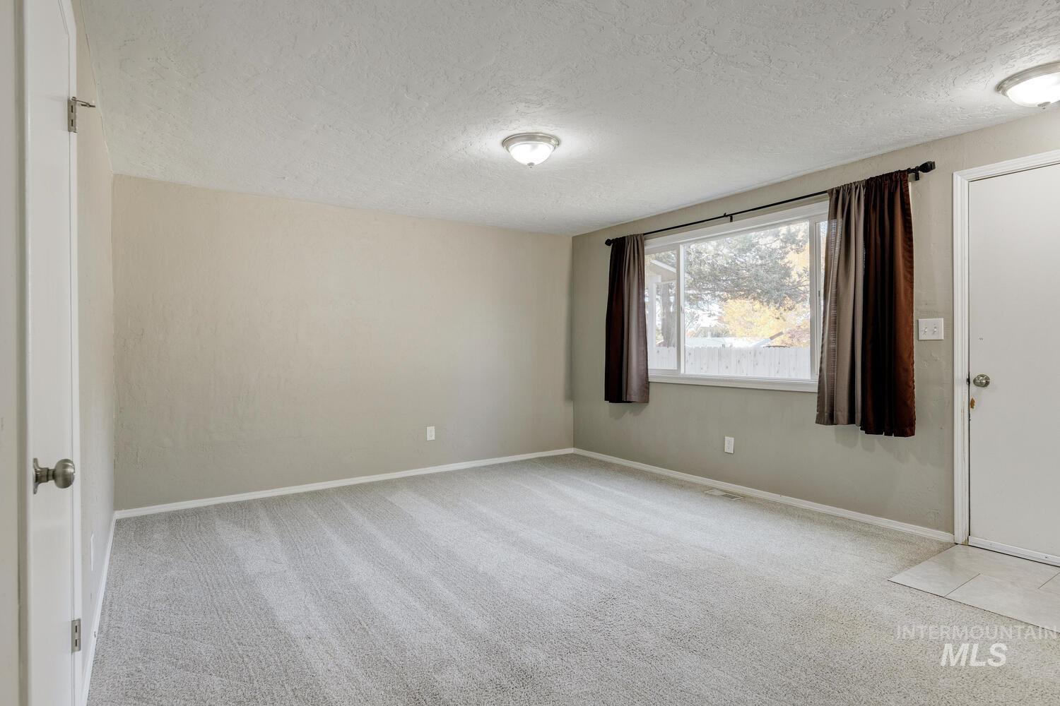 Carpeted empty room featuring baseboards and a textured ceiling