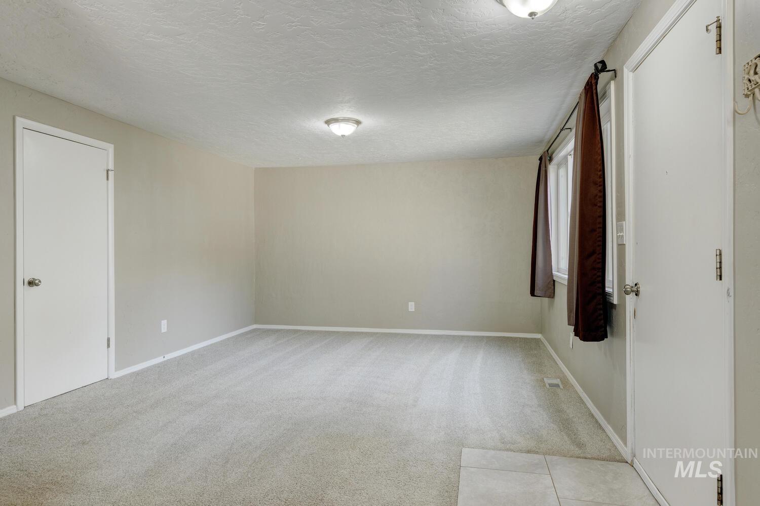 Unfurnished room featuring light carpet and a textured ceiling