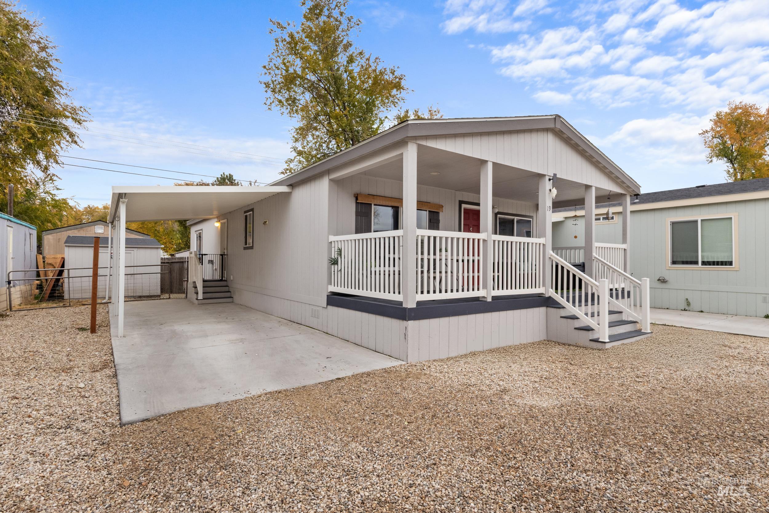 Manufactured / mobile home featuring a porch, a carport, and a shed