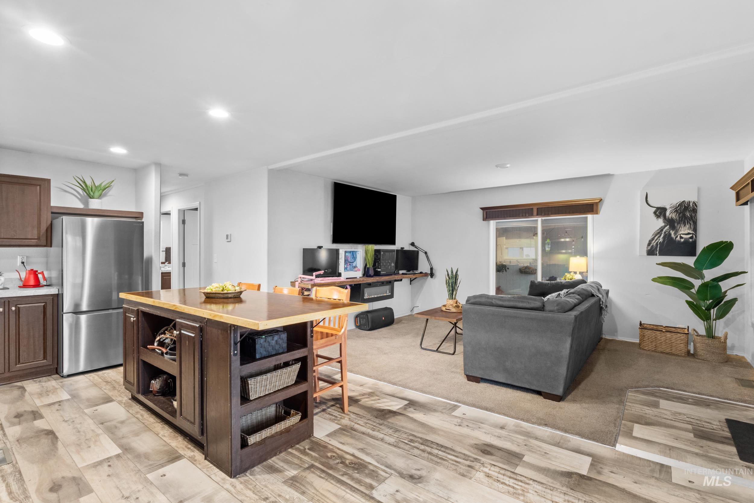 Kitchen featuring open shelves, dark brown cabinets, freestanding refrigerator, open floor plan, and recessed lighting