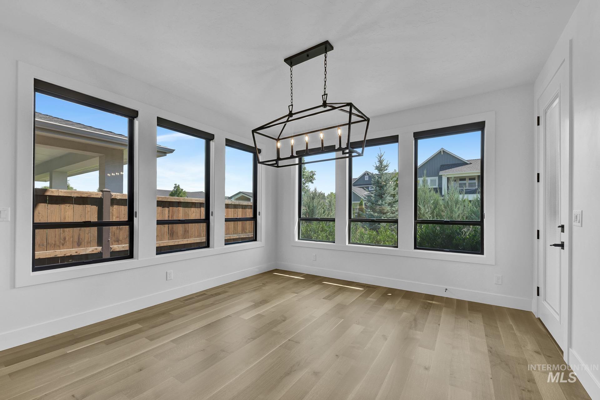 Unfurnished sunroom with a chandelier, plenty of natural light, and wood finished floors
